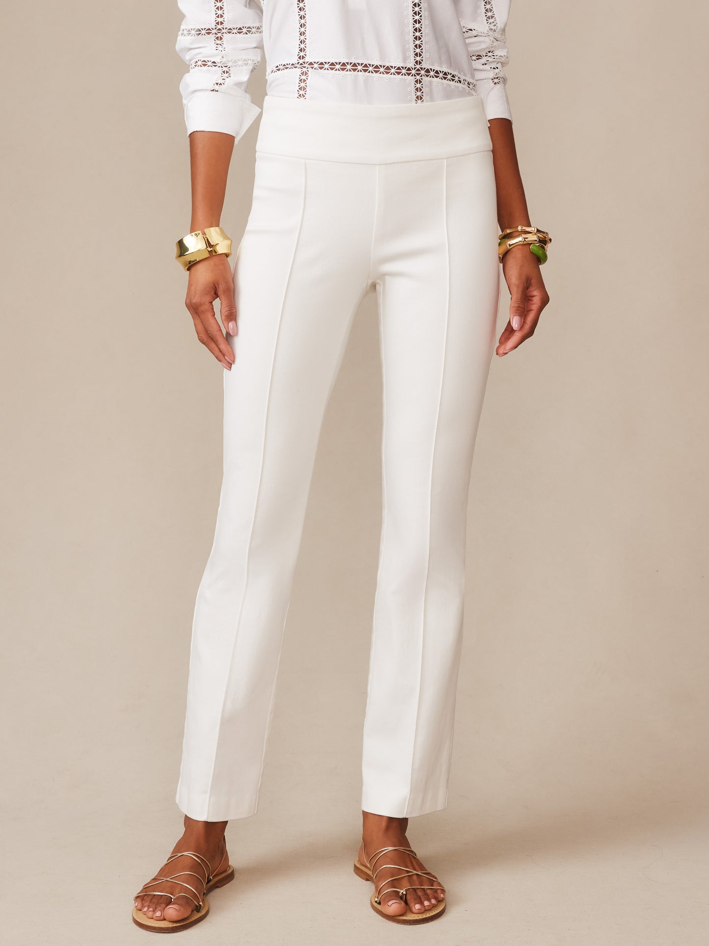 A model wearing white Rylie Jeans by J.McLaughlin, featuring a classic fit with clean lines and a high waist, paired with gold bangles and strappy sandals, showcasing effortlessly stylish, enduring designs and innovative fabrics from a legacy of timeless fashion. A destination for defining style. Life, Well-Lived.