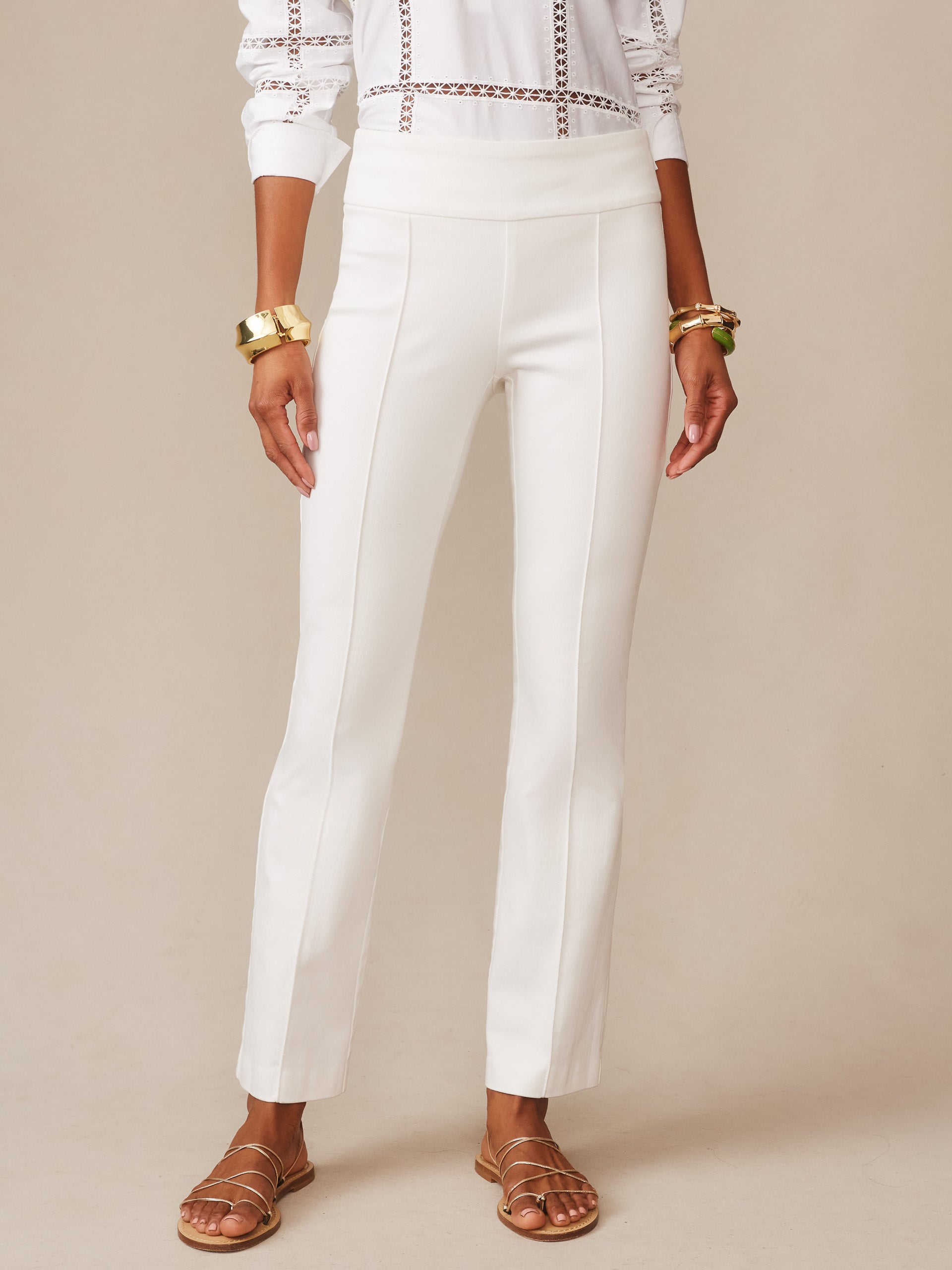 A model wearing white Rylie Jeans by J.McLaughlin, featuring a classic fit with clean lines and a high waist, paired with gold bangles and strappy sandals, showcasing effortlessly stylish, enduring designs and innovative fabrics from a legacy of timeless fashion. A destination for defining style. Life, Well-Lived.