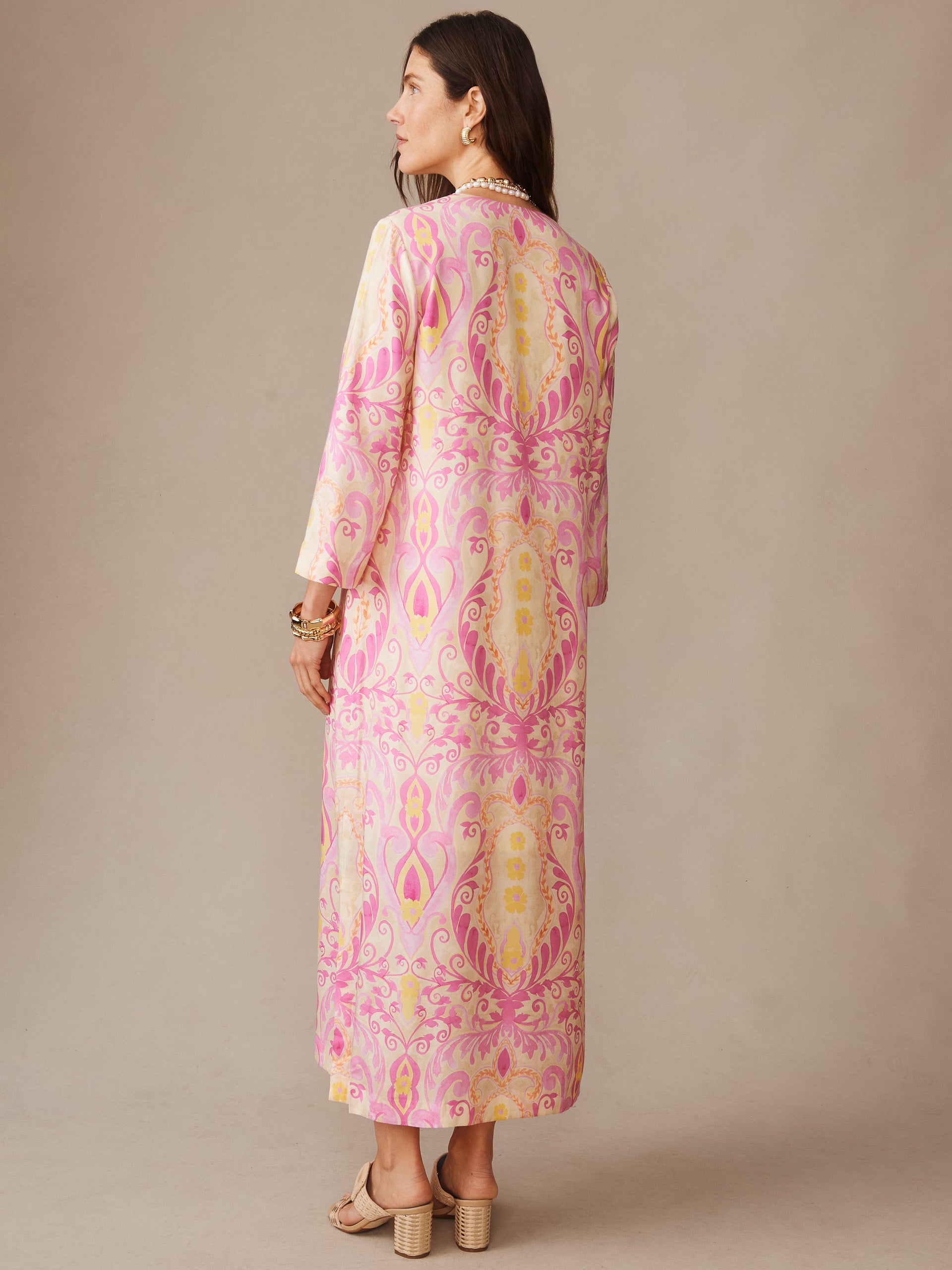 A woman wearing the Roni Silk Blend Dress in Midi Deco Bloom by J.McLaughlin, featuring an effortlessly stylish, flowing midi-length dress in soft pink and cream paisley patterns that embodies enduring designs and innovative fabrics. A destination for defining style. Life, Well-Lived.