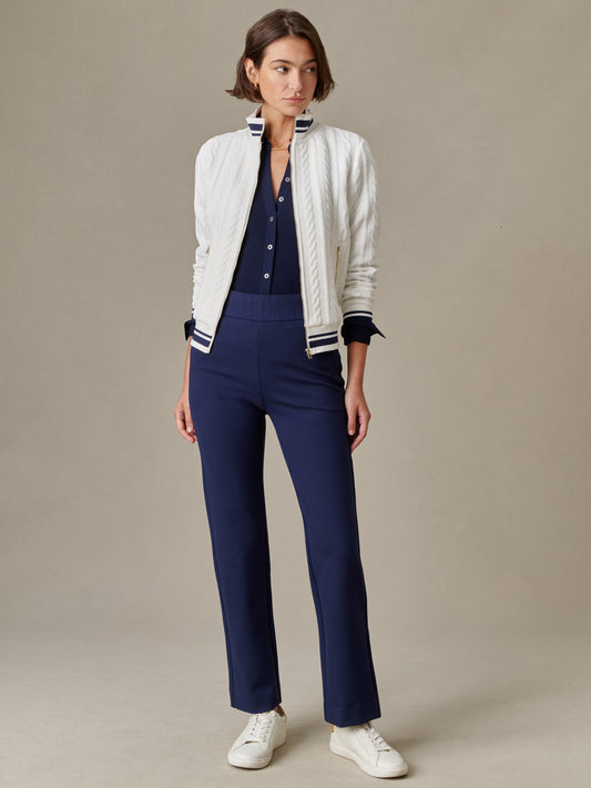 Woman wearing navy Rory Pants by J.McLaughlin paired with a navy button-up shirt, white textured jacket, and white sneakers, showcasing timeless style and craftsmanship.