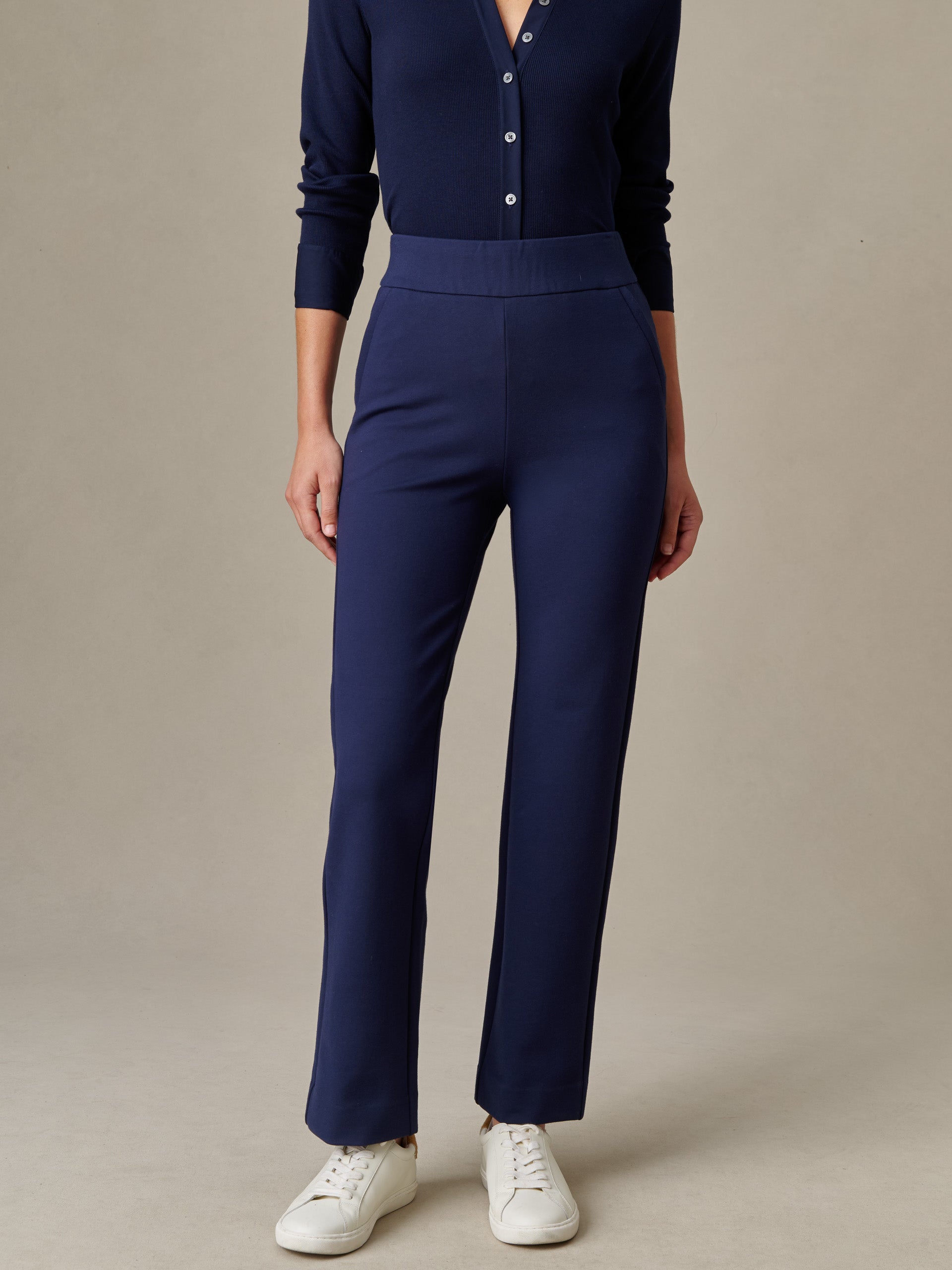Woman wearing navy Rory Pants by J.McLaughlin paired with a navy buttoned top and white sneakers, showcasing effortlessly stylish, enduring design perfect for timeless fashion.