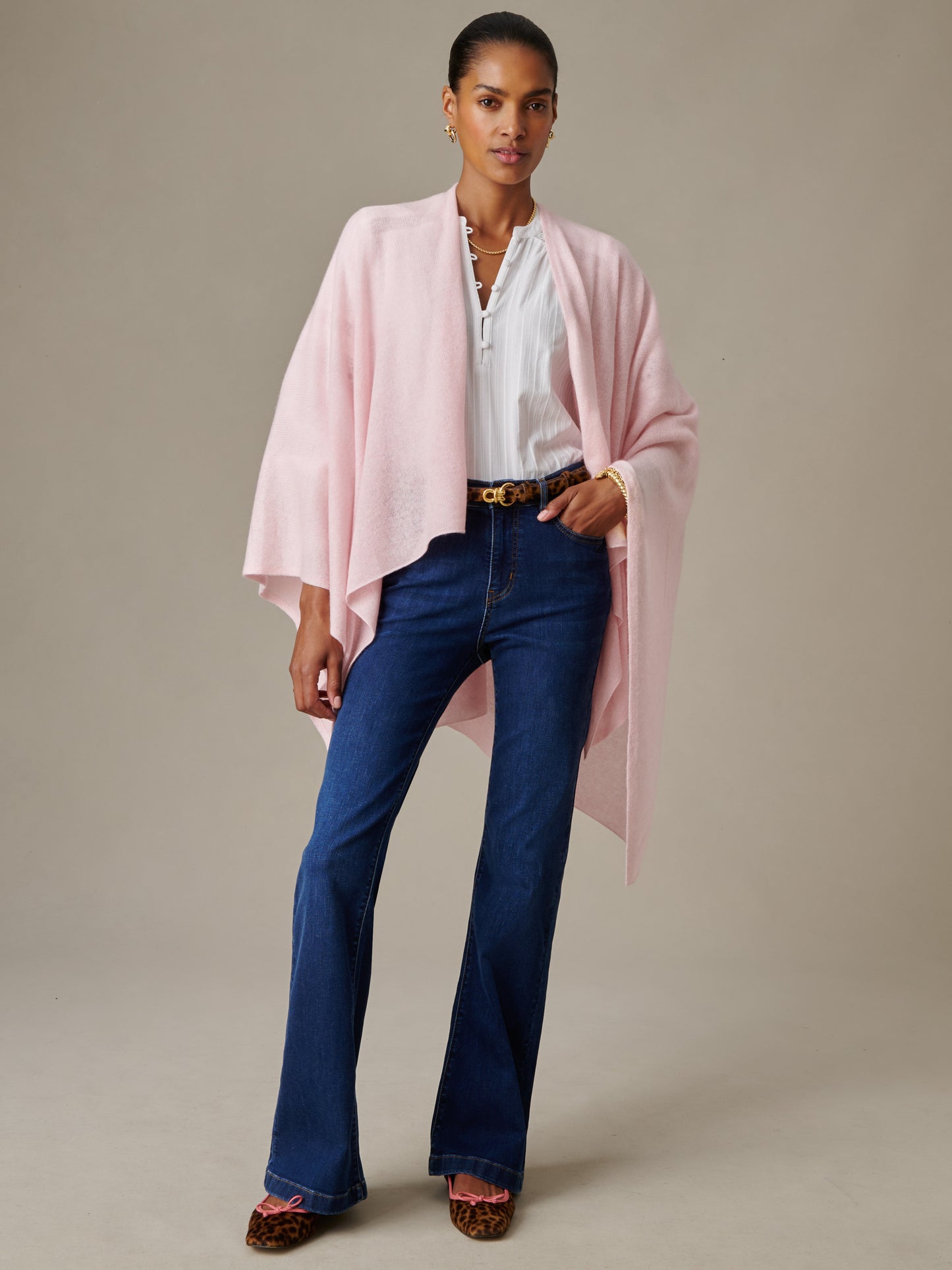 Woman wearing a soft pink Rossi Cashmere Wrap layered over a white blouse and dark blue jeans with leopard print shoes, showcasing J.McLaughlin's effortlessly stylish, enduring design.