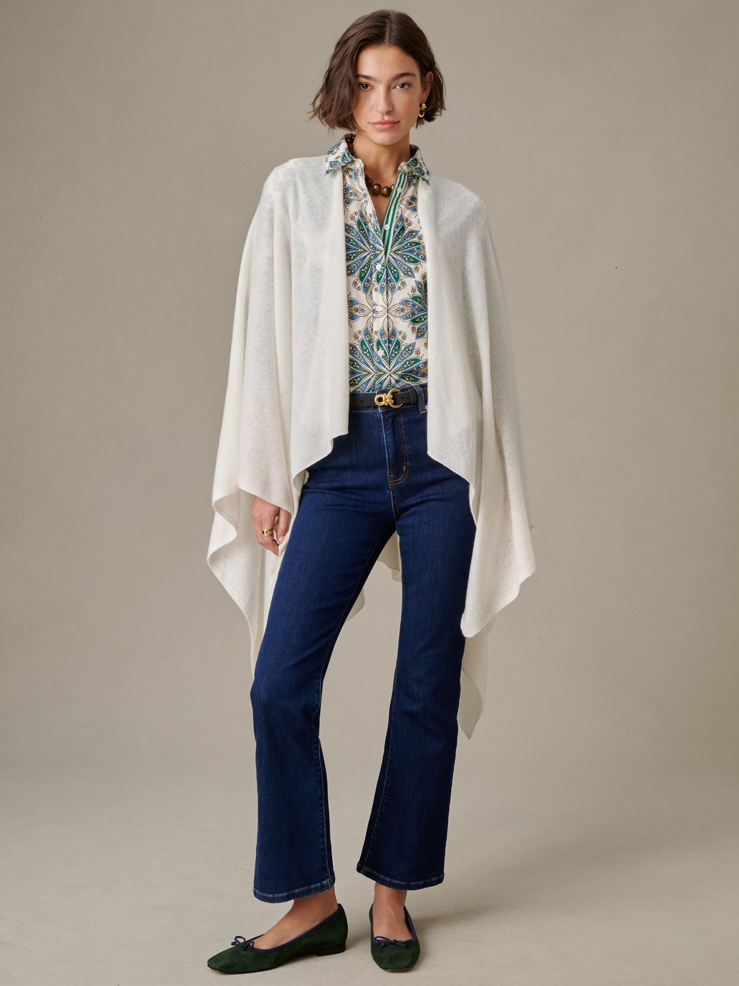 Woman wearing a patterned blouse, dark blue jeans, green flats, and a soft white Rossi Cashmere Wrap by J.McLaughlin, showcasing an effortlessly stylish and timeless look.