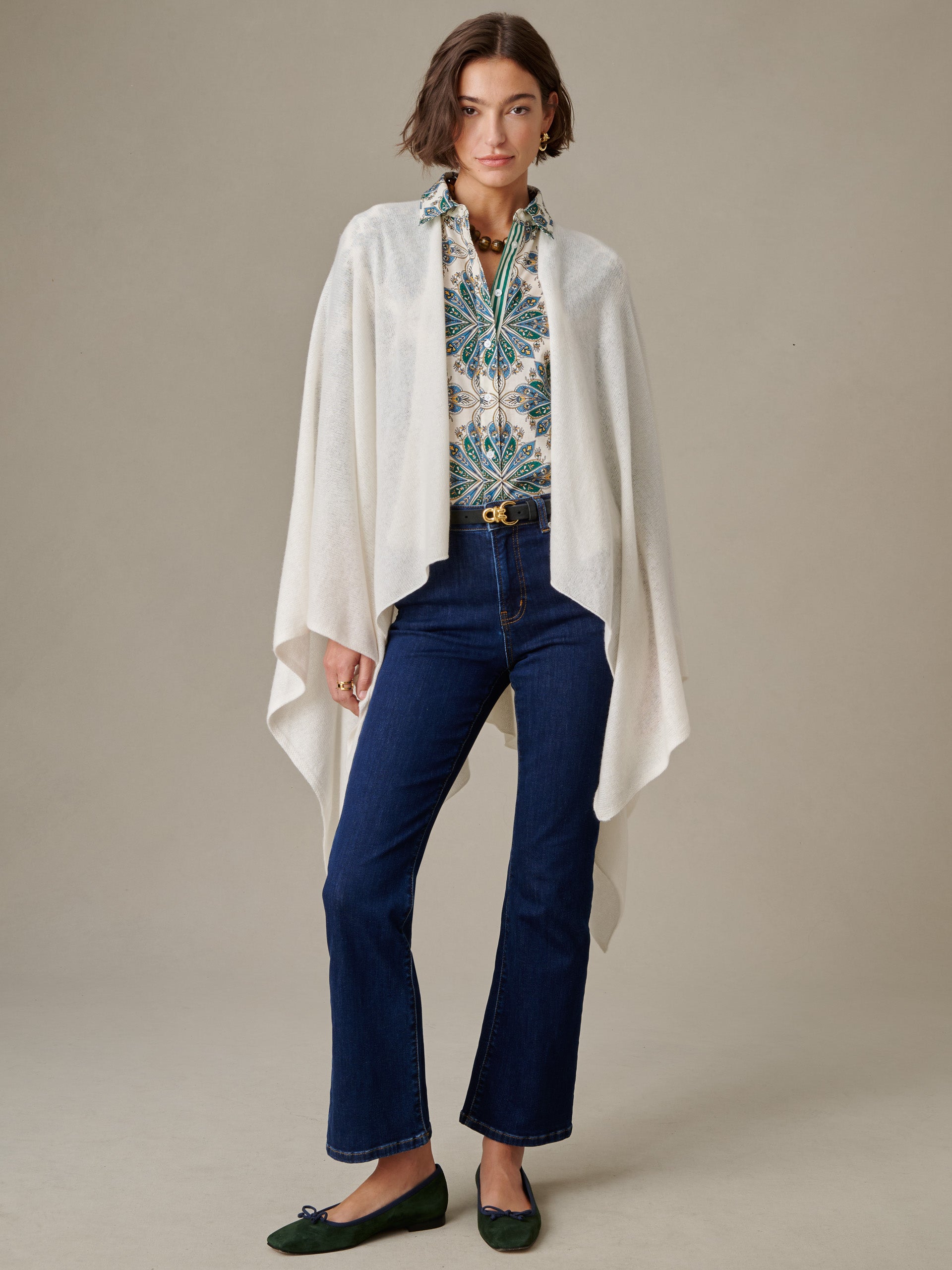 Woman wearing a patterned blouse, dark blue jeans, green flats, and a soft white Rossi Cashmere Wrap by J.McLaughlin, showcasing an effortlessly stylish and timeless look.