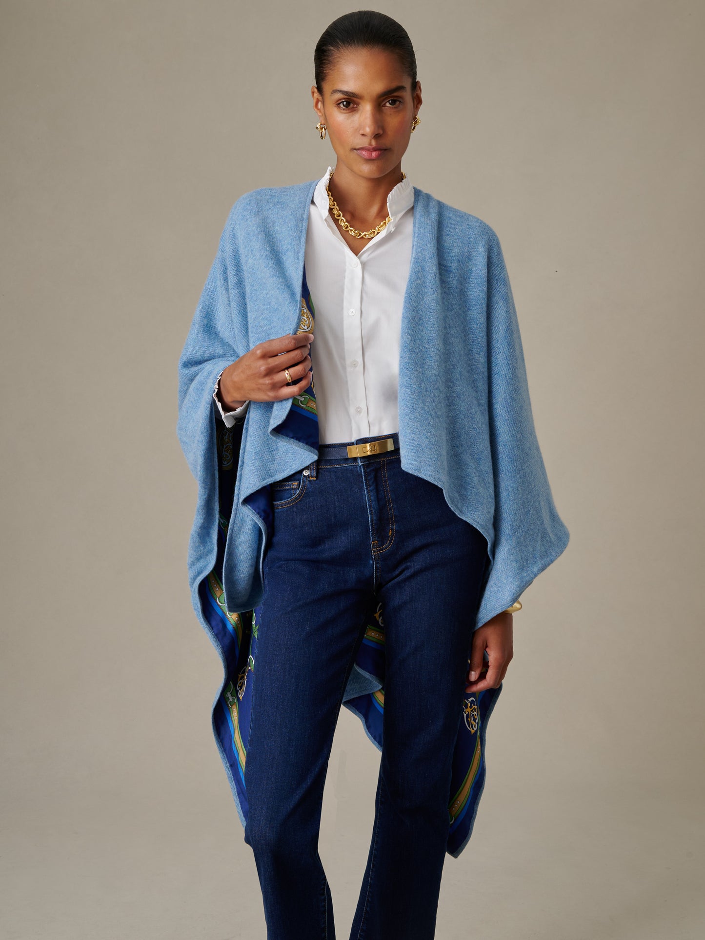 Woman wearing a blue Rossi Cashmere Wrap in Fairfax Crest by J.McLaughlin over a white blouse and dark jeans, showcasing effortlessly stylish, enduring design in classic, timeless fashion.