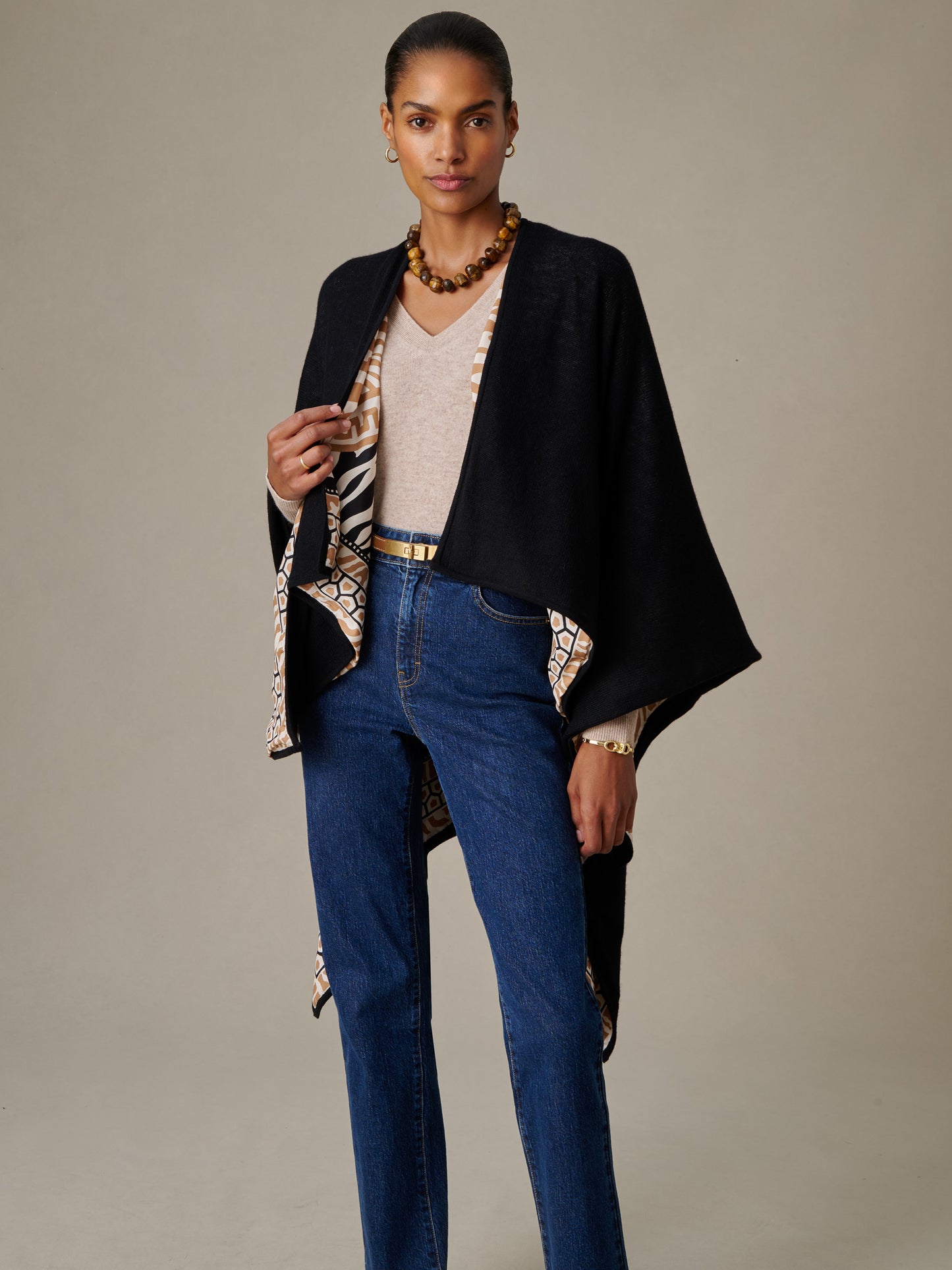 Woman wearing a Rossi Cashmere Wrap in Wild Medley Border by J.McLaughlin over a beige top and blue jeans, showcasing effortlessly stylish, timeless design with a patterned border.
