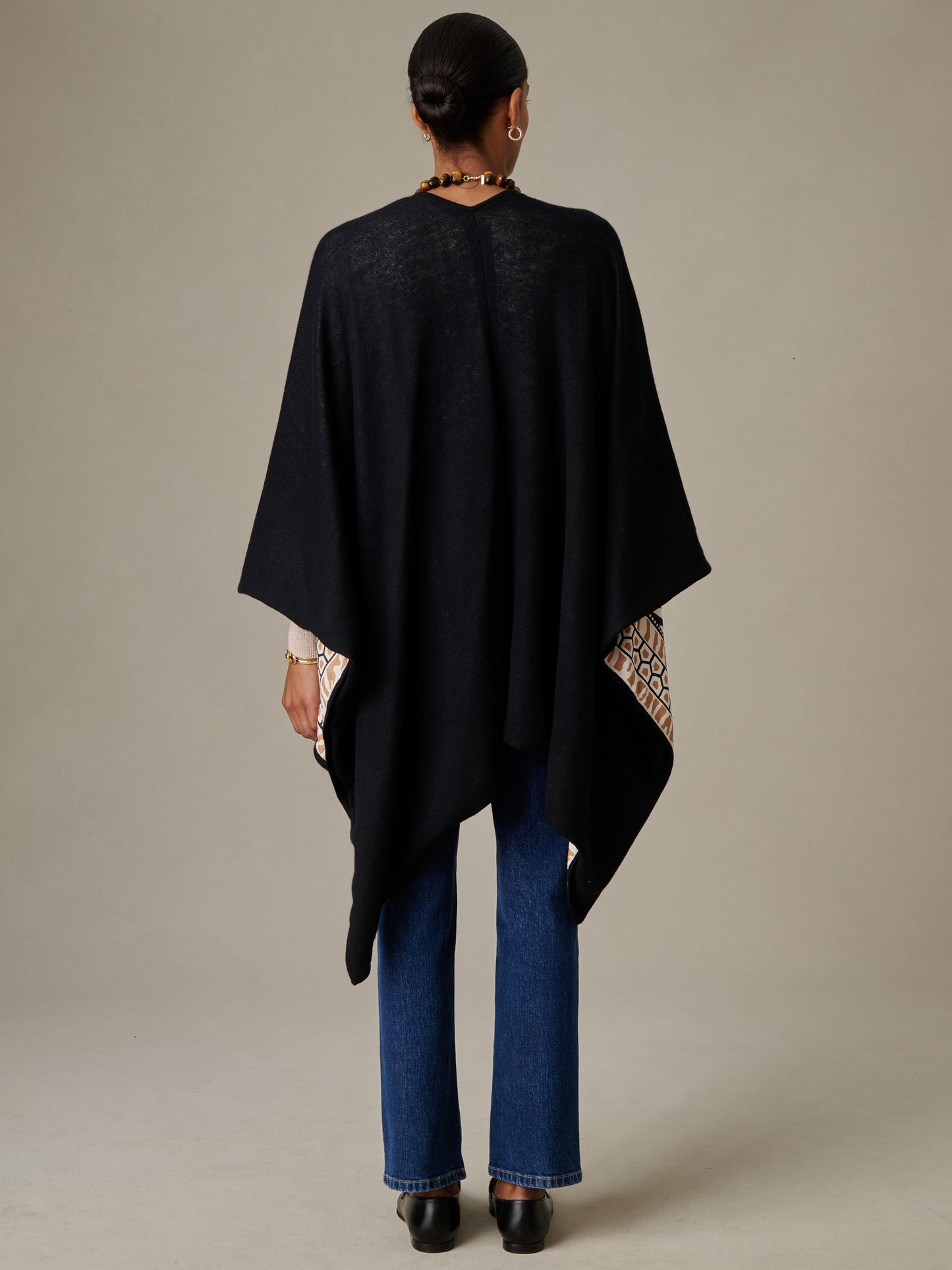 Woman seen from behind wearing a black Rossi Cashmere Wrap in Wild Medley Border over blue jeans, styled by J.McLaughlin for an effortlessly stylish, timeless look.