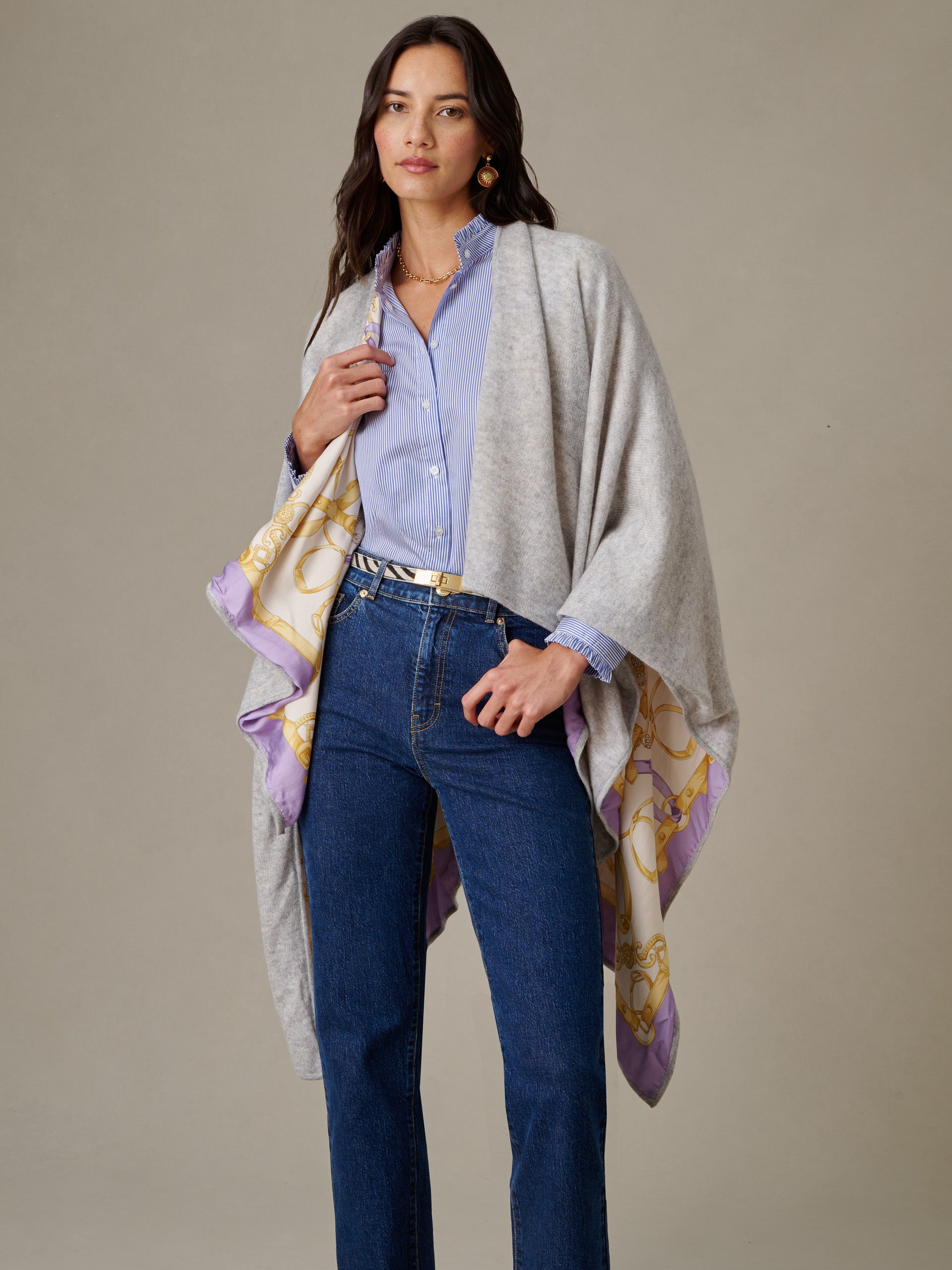 Woman wearing a Rossi Cashmere Wrap in Grand Heraldic Border over a light blue blouse and dark jeans, styled by J.McLaughlin for an effortlessly stylish and timeless look.