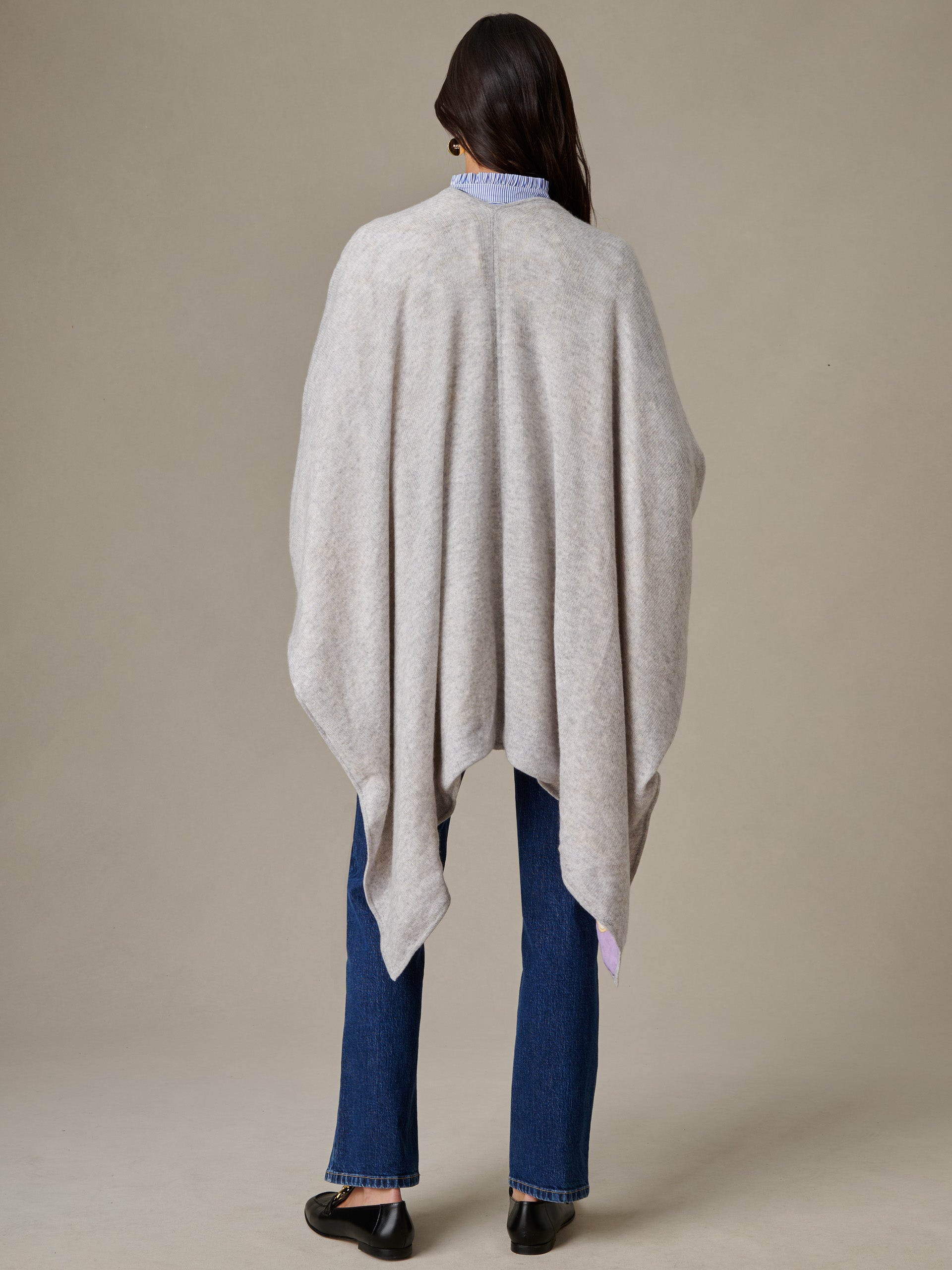 Woman wearing a Rossi Cashmere Wrap in Grand Heraldic Border draped over shoulders, paired with jeans and black shoes, showcasing effortless style by J.McLaughlin.