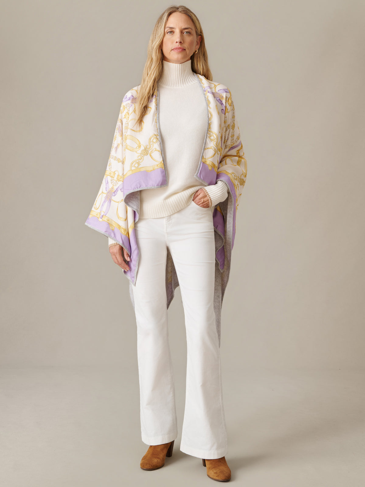 Model wearing the Rossi Cashmere Wrap in Grand Heraldic Border by J.McLaughlin over a white sweater and pants with brown shoes
