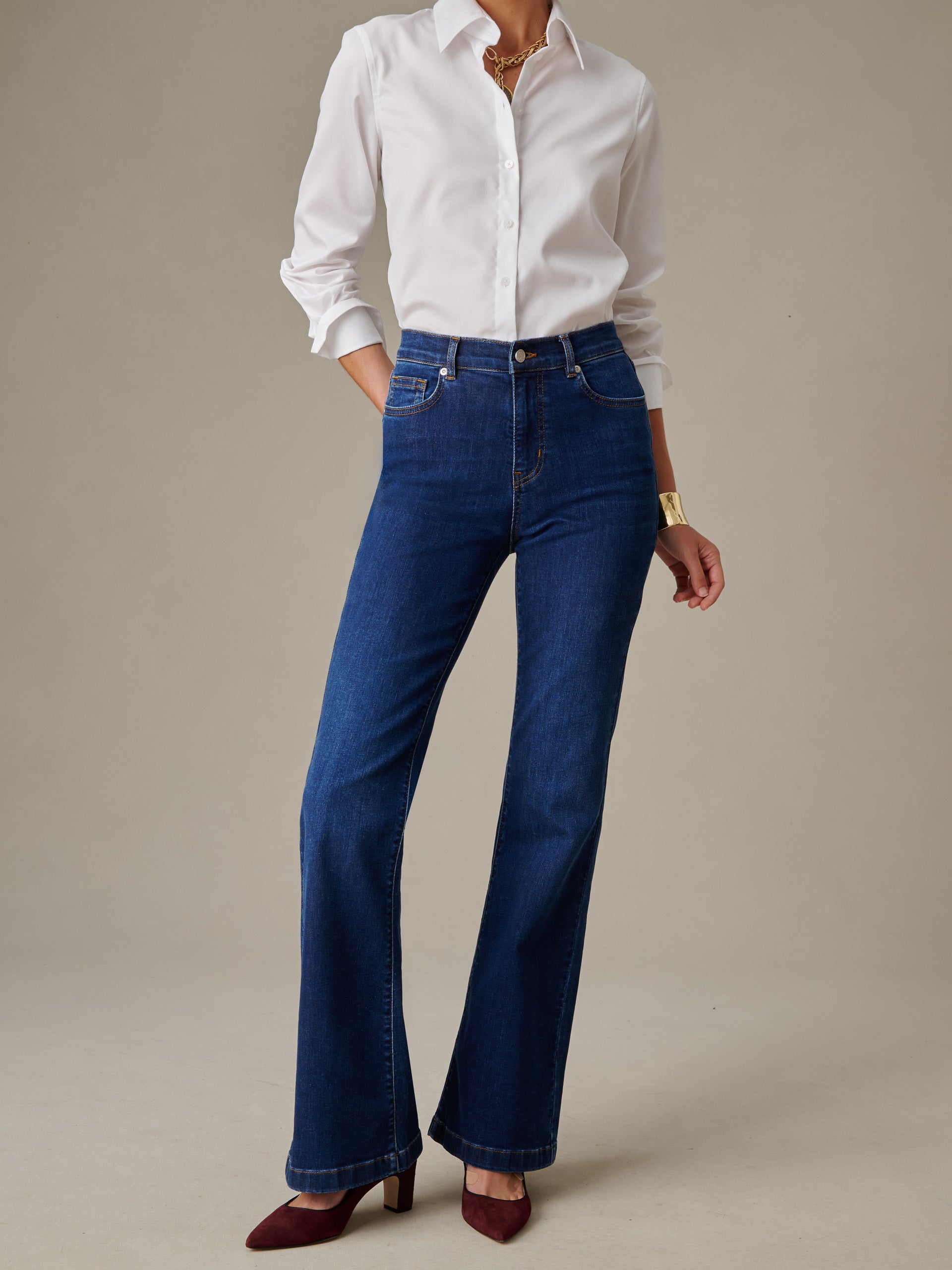 Woman wearing J. McLaughlin Domino Jeans paired with a classic white button-down shirt and burgundy heels, showcasing effortlessly stylish and enduring designs.
