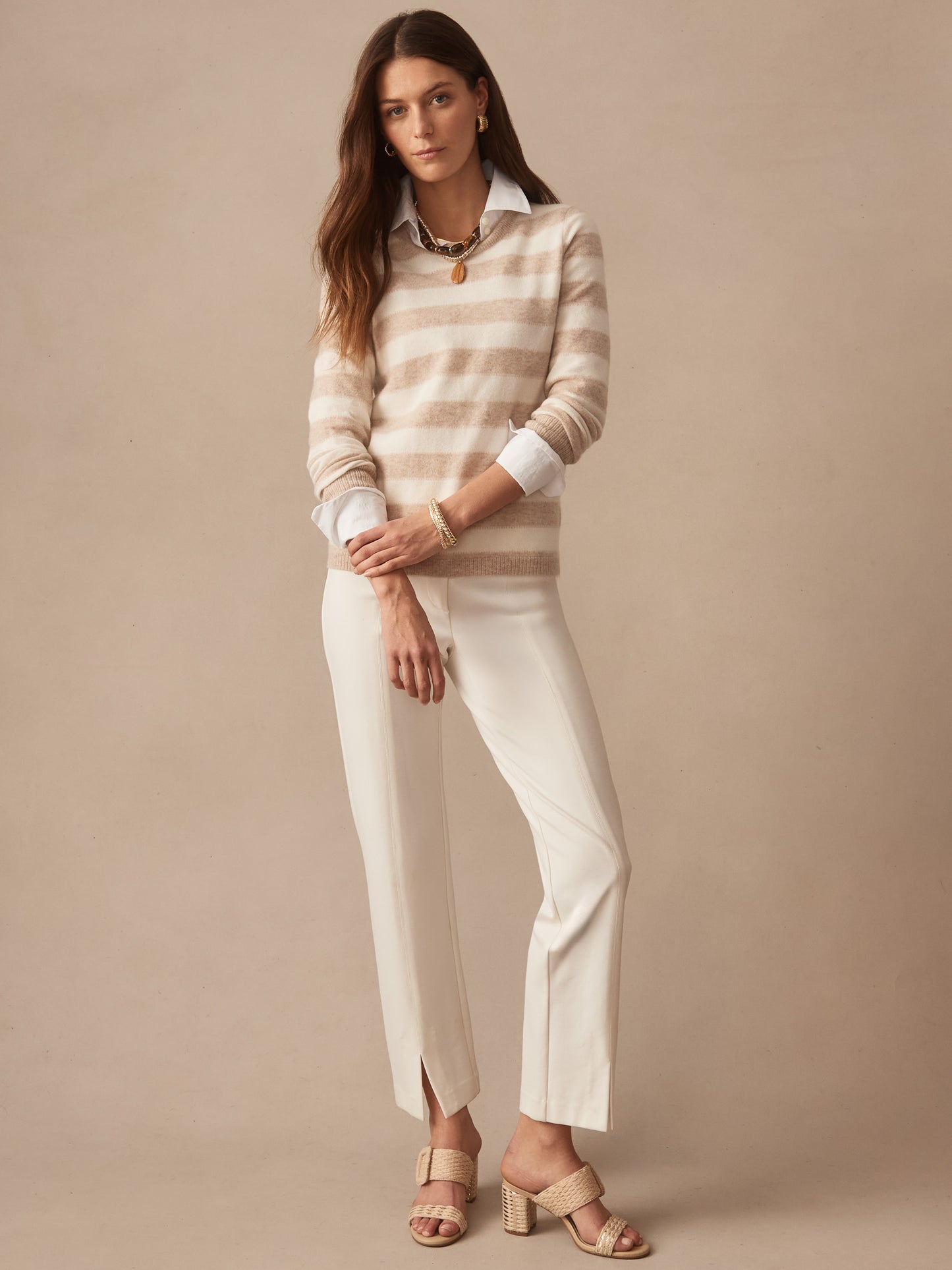 Woman wearing a Ruby Cashmere Sweater in Stripe in soft oatmeal and ivory tones by J.McLaughlin, styled with white pants and woven heeled sandals, embodying effortlessly stylish, enduring designs and innovative fabrics from a destination for defining style. Life, Well-Lived.