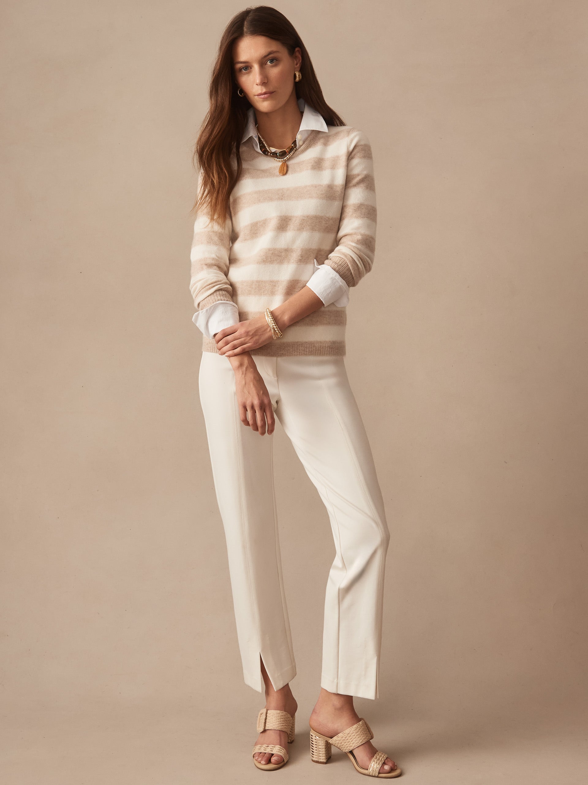 Woman wearing a Ruby Cashmere Sweater in Stripe in soft oatmeal and ivory tones by J.McLaughlin, styled with white pants and woven heeled sandals, embodying effortlessly stylish, enduring designs and innovative fabrics from a destination for defining style. Life, Well-Lived.