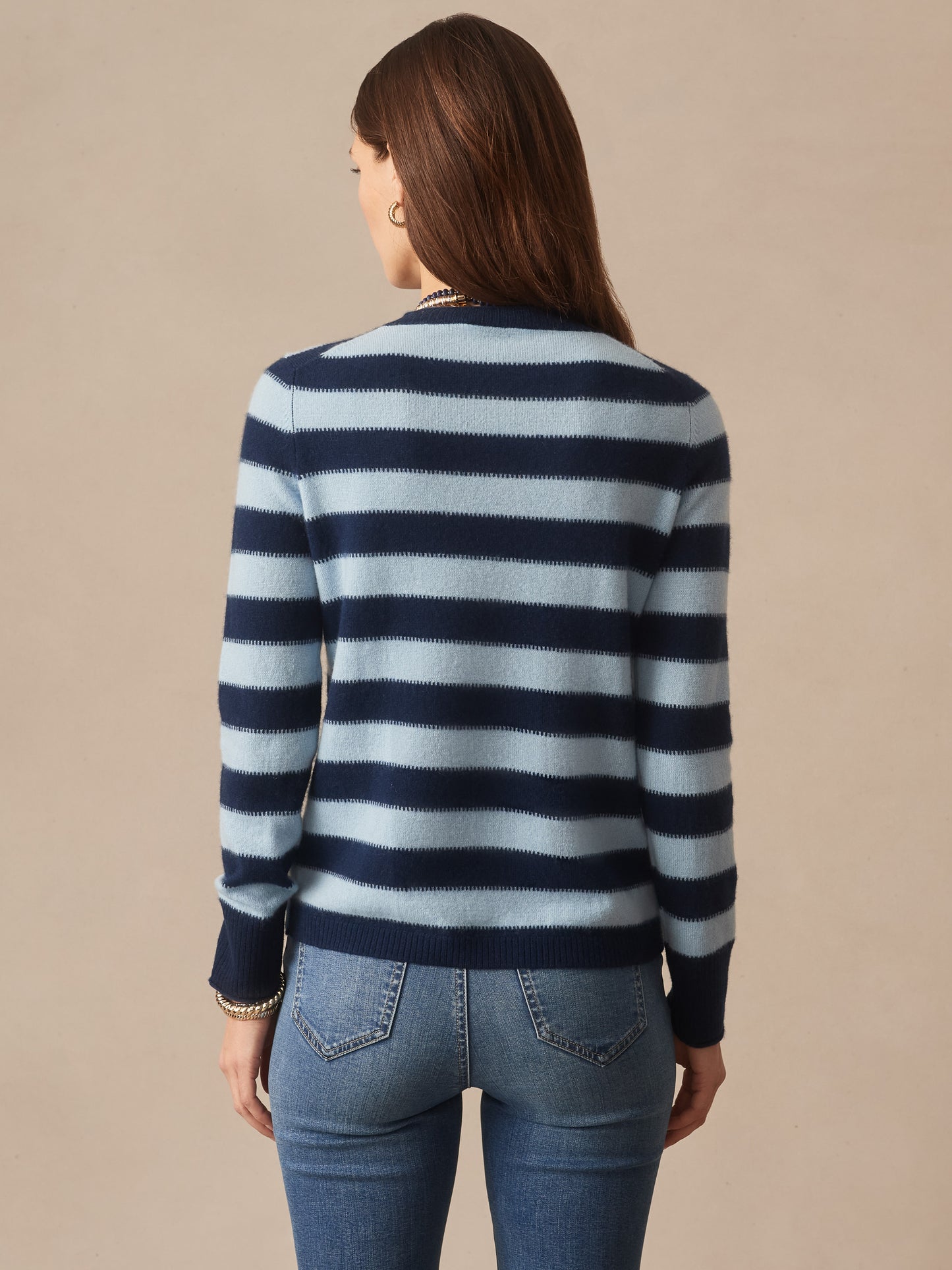 Woman seen from behind wearing a Ruby Cashmere Sweater in Stripe by J.McLaughlin in navy and light blue, paired with jeans, showcasing effortlessly stylish, enduring designs.