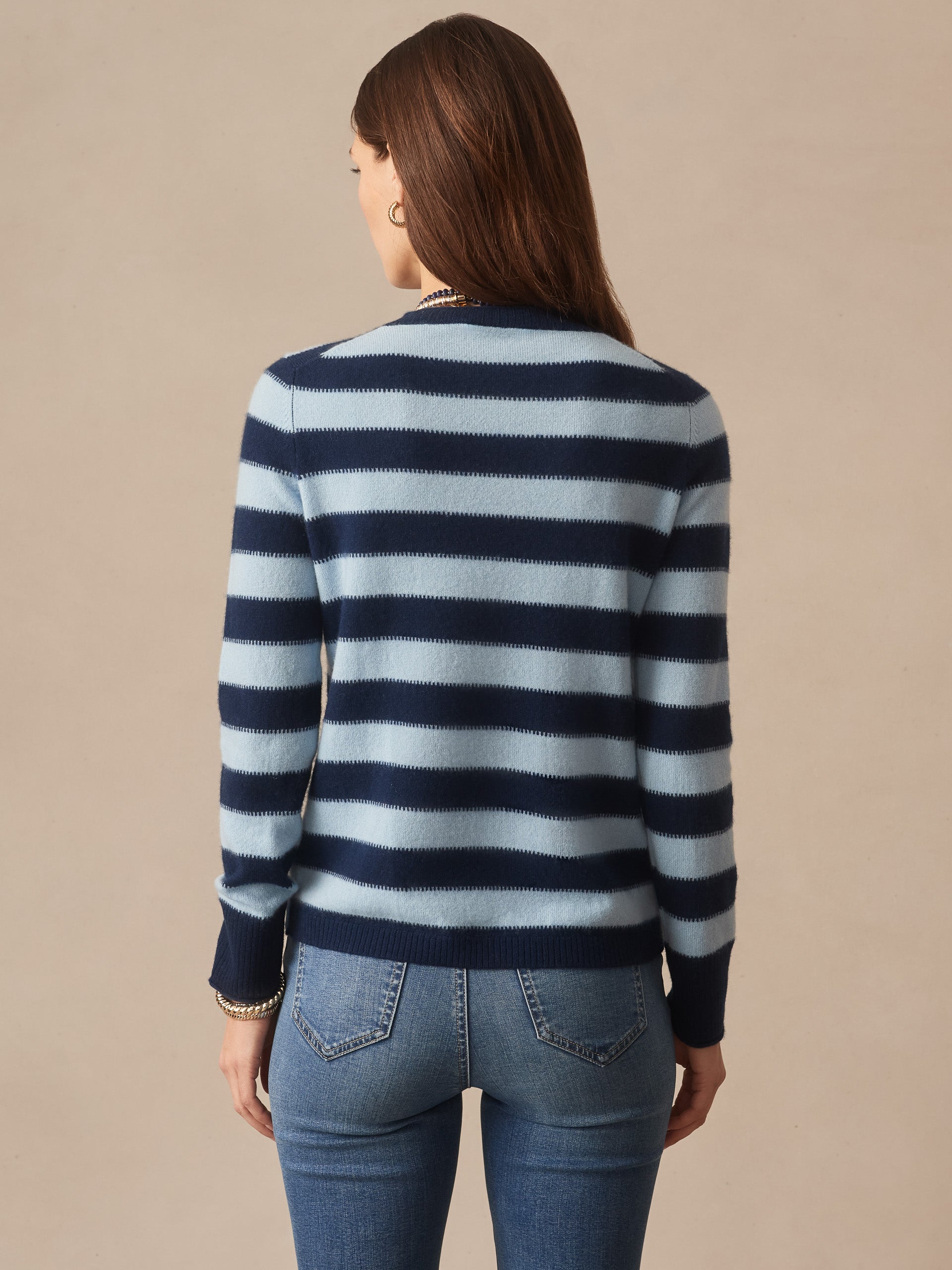 Woman seen from behind wearing a Ruby Cashmere Sweater in Stripe by J.McLaughlin in navy and light blue, paired with jeans, showcasing effortlessly stylish, enduring designs.