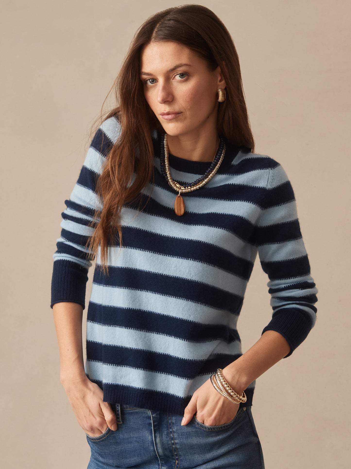 Woman wearing a Ruby Cashmere Sweater in Stripe by J.McLaughlin, featuring navy and light blue horizontal stripes, paired with casual jeans and gold jewelry, embodying effortlessly stylish, enduring designs in innovative fabrics, a destination for defining style. Life, Well-Lived.