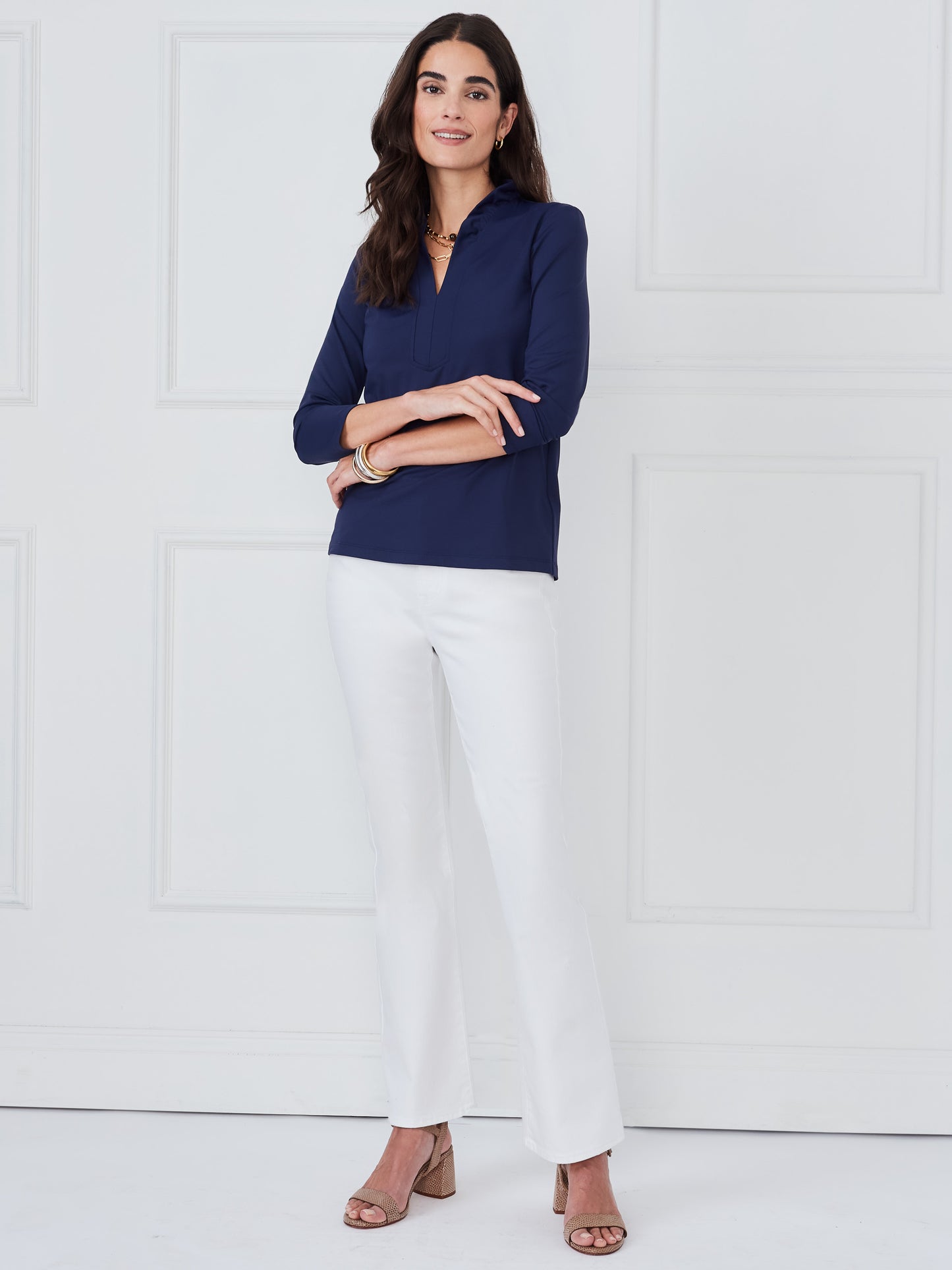 Woman wearing a navy Kate Ruffle Top by J.McLaughlin paired with white pants and sandals, showcasing effortlessly stylish, enduring designs from a destination for defining style. Life, Well-Lived.