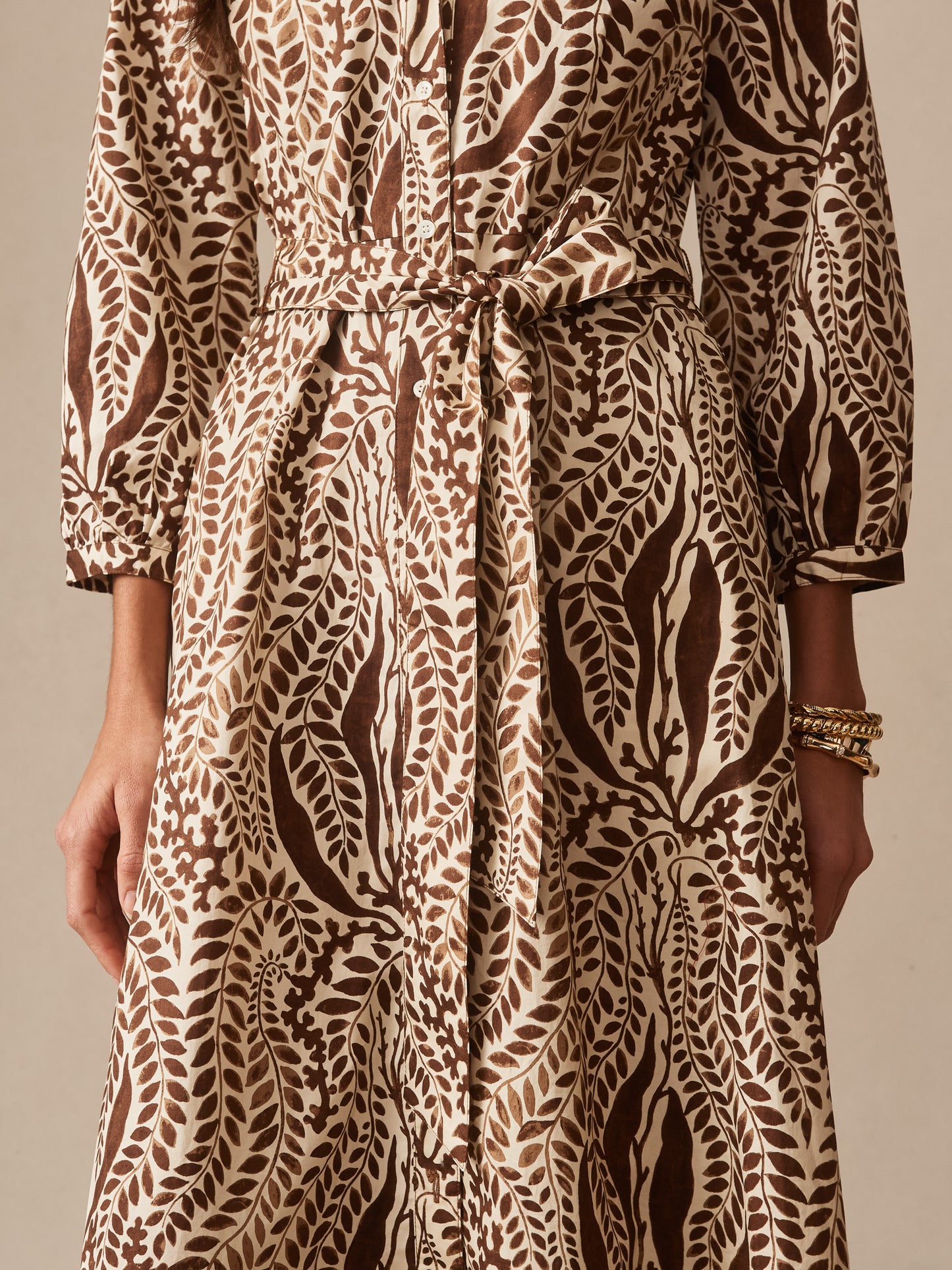 Close-up of a patterned dress with a brown and tan botanical print featuring a tied waist belt and long sleeves, showcasing the J.McLaughlin Sena Dress in Coral Current, embodying effortlessly stylish, enduring designs with innovative fabrics, a destination for defining style. Life, Well-Lived.