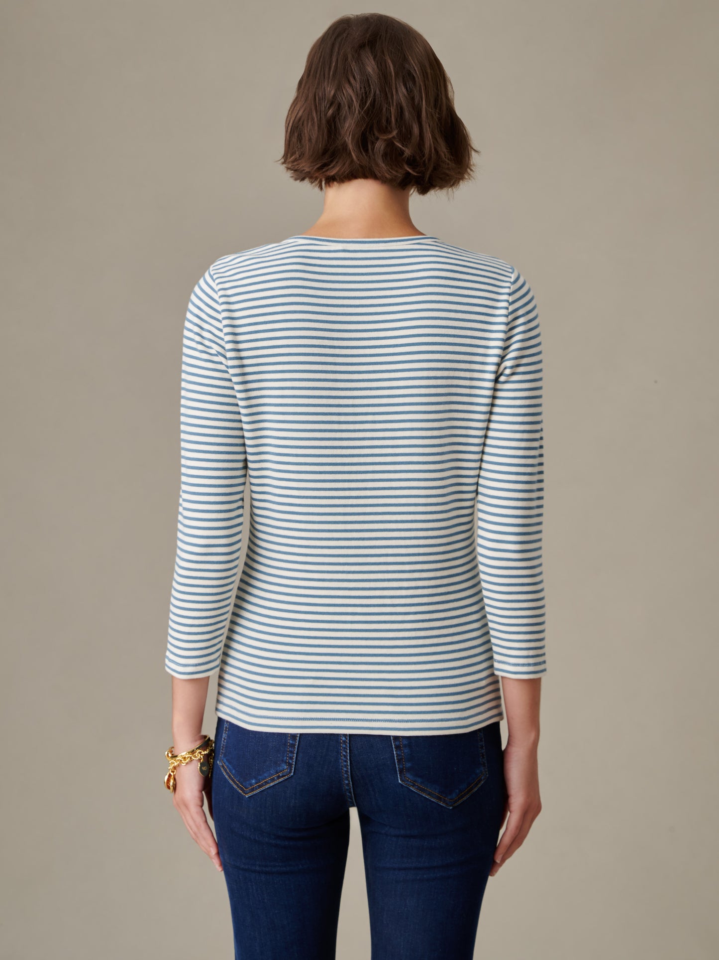 Woman seen from the back wearing a Sinclair Henley in Stripe by J.McLaughlin, featuring a classic striped shirt paired with dark jeans, showcasing timeless style and quality craftsmanship.