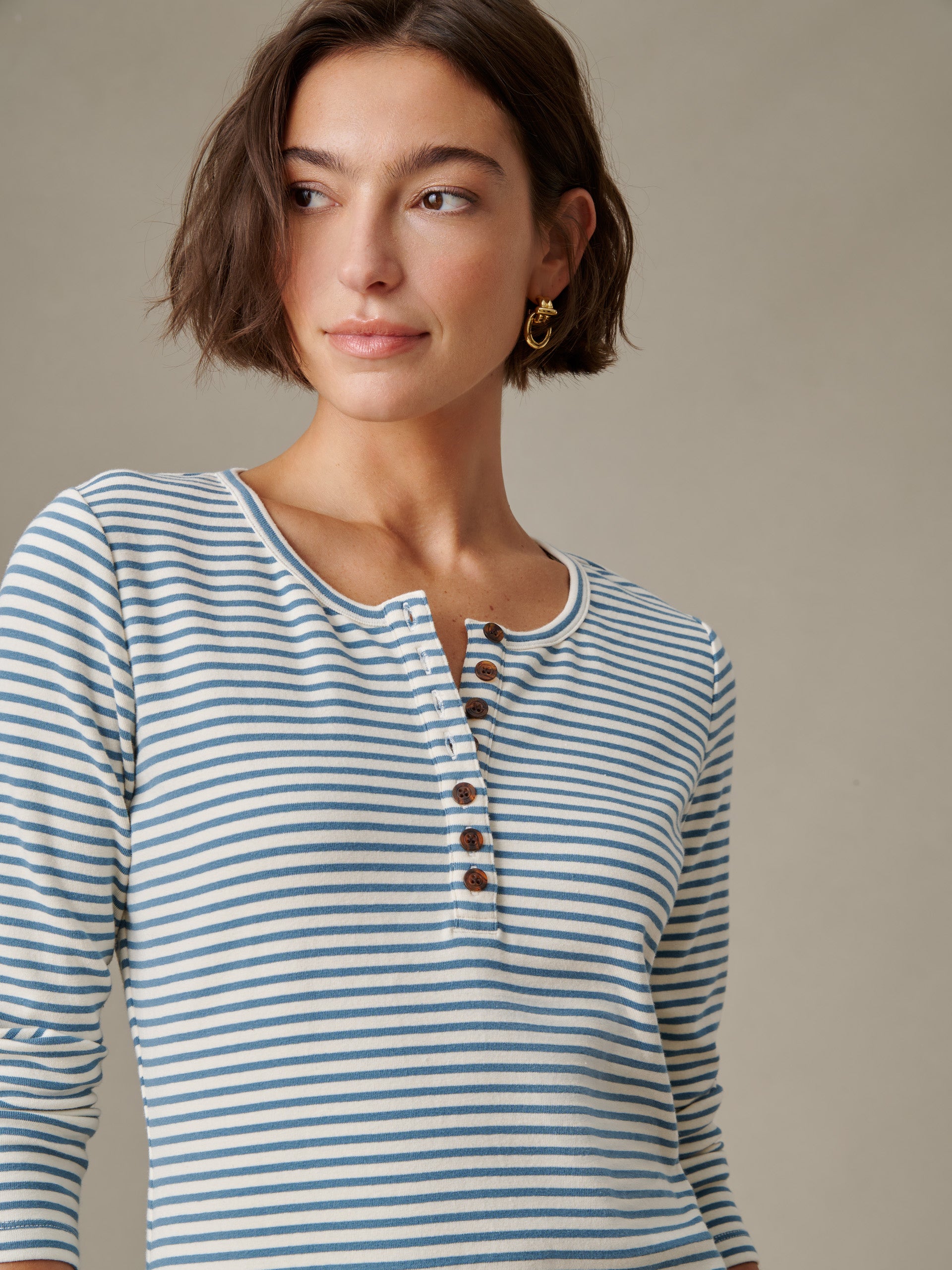 Woman wearing a Sinclair Henley in Stripe by J.McLaughlin, featuring blue and white horizontal stripes and button details, embodying timeless, effortlessly stylish design.
