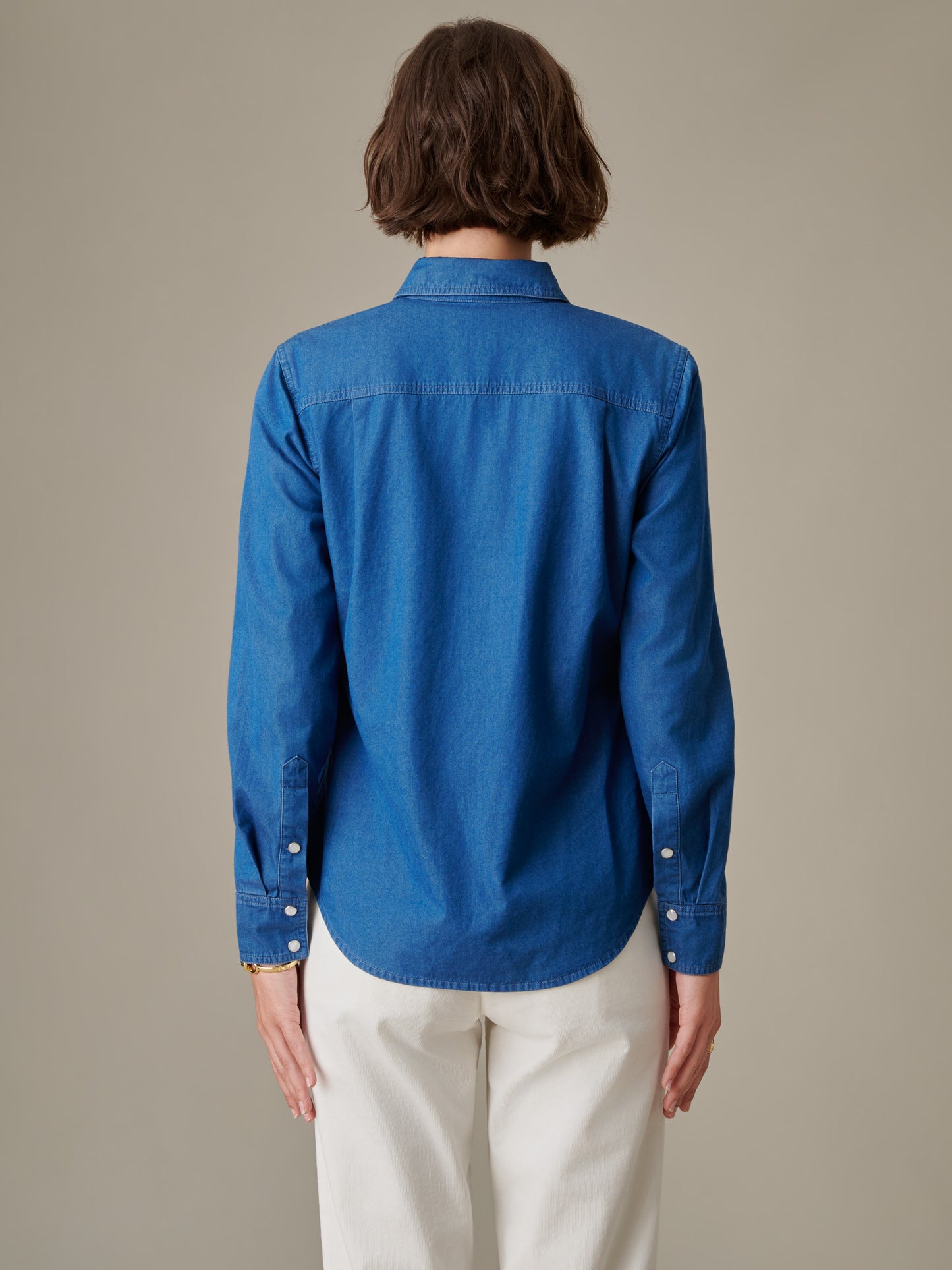 Back view of a person wearing a blue Lois Chambray Shirt by J.McLaughlin, showcasing the shirt’s clean lines and classic, enduring design in innovative fabric.