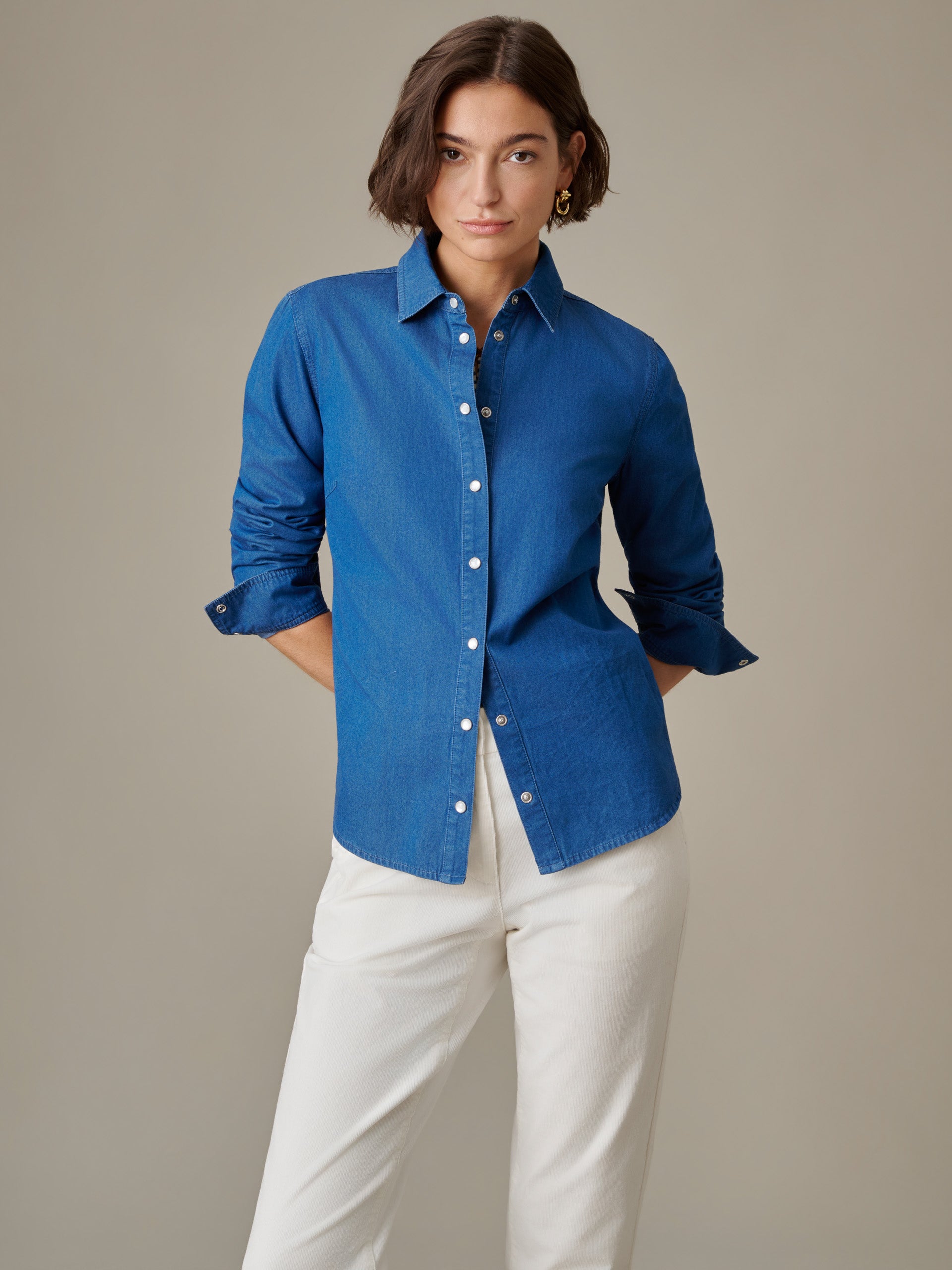 Woman wearing a blue Lois Chambray Shirt by J.McLaughlin paired with white pants, showcasing a classic, effortlessly stylish look with enduring design and quality craftsmanship.