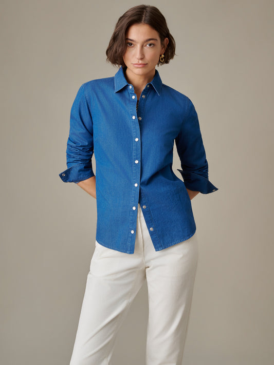 Woman wearing a blue Lois Chambray Shirt by J.McLaughlin paired with white pants, showcasing a classic, effortlessly stylish look with enduring design and quality craftsmanship.