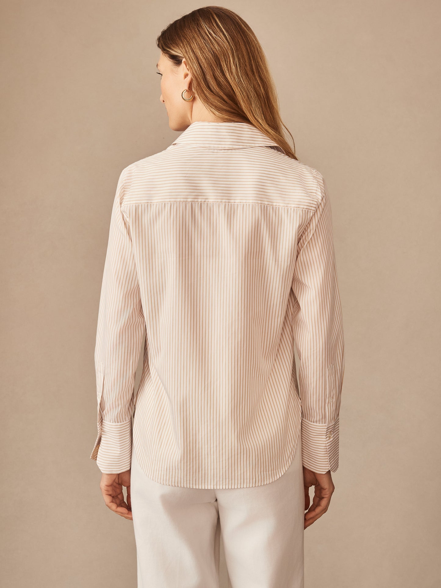 A woman wearing the Sloane Shirt in Stripe by J.McLaughlin, showcasing effortlessly stylish, enduring designs with innovative fabrics for a legacy of timeless fashion. A destination for defining style. Life, Well-Lived.
