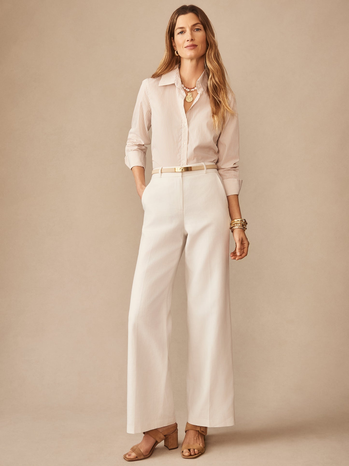 A woman wearing the Sloane Shirt in Stripe by J.McLaughlin, styled with wide-leg trousers and accessories, showcasing effortlessly stylish, enduring designs in innovative fabrics from a destination for defining style. Life, Well-Lived.