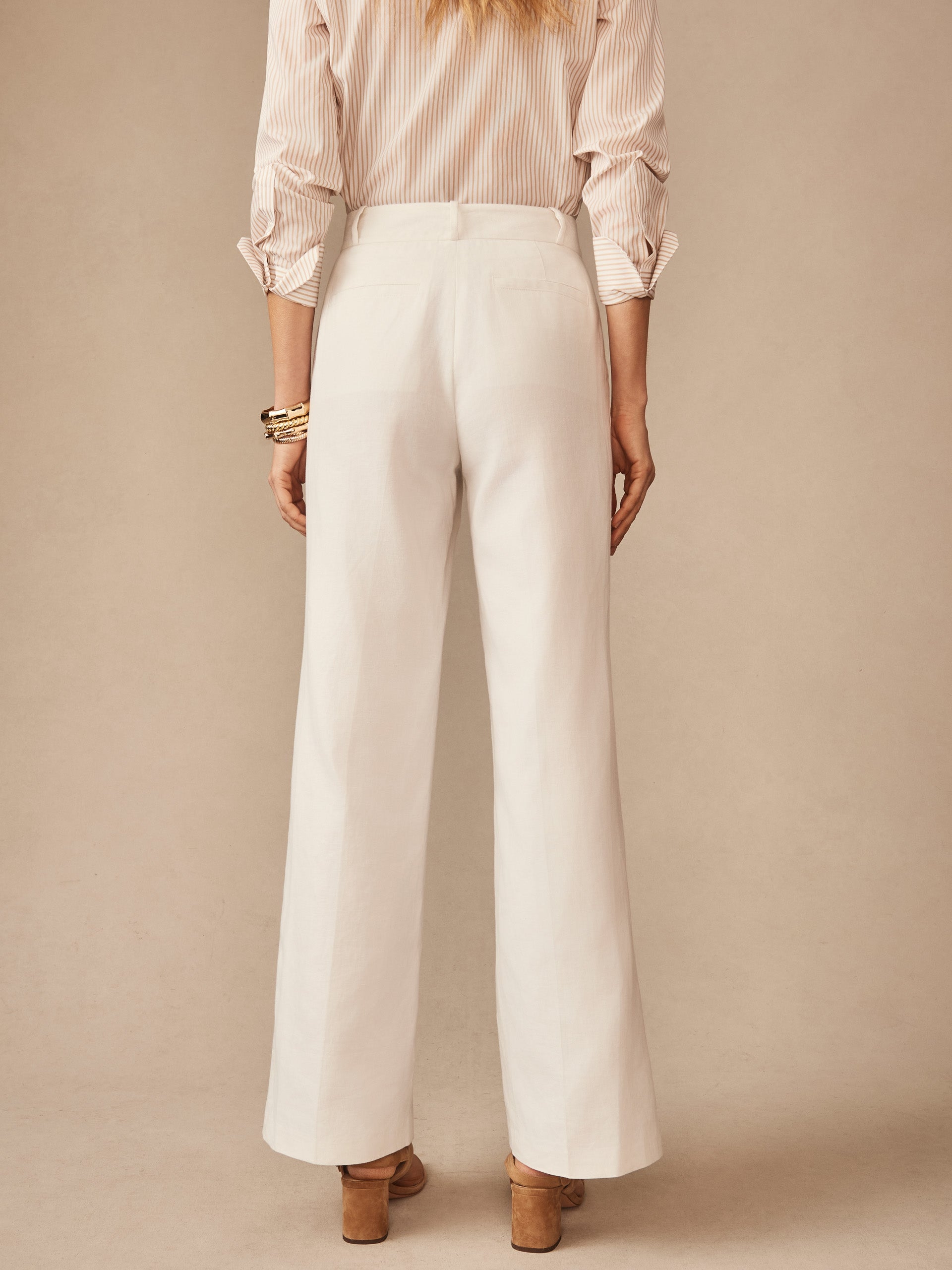 Back view of a woman wearing white Blythe Linen Blend Pants by J.McLaughlin paired with a striped blouse, showcasing effortlessly stylish and enduring designs with innovative fabrics.