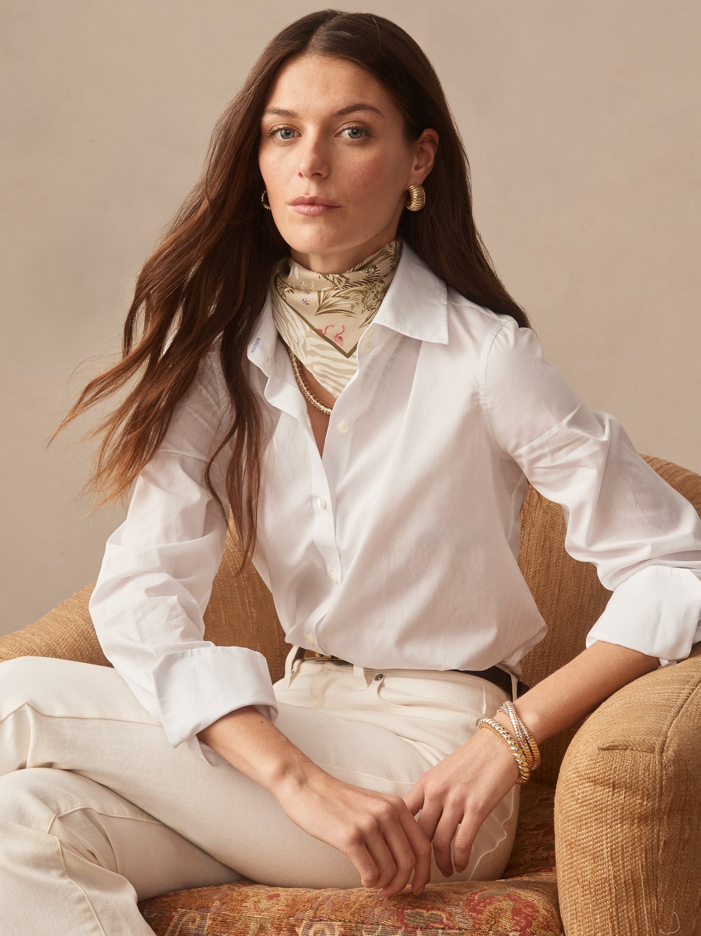 Woman wearing J.McLaughlin Nikka Silk Scarf in Zebra Story Court styled with classic white shirt and cream pants, embodying effortlessly stylish, enduring designs and legacy of timeless fashion.