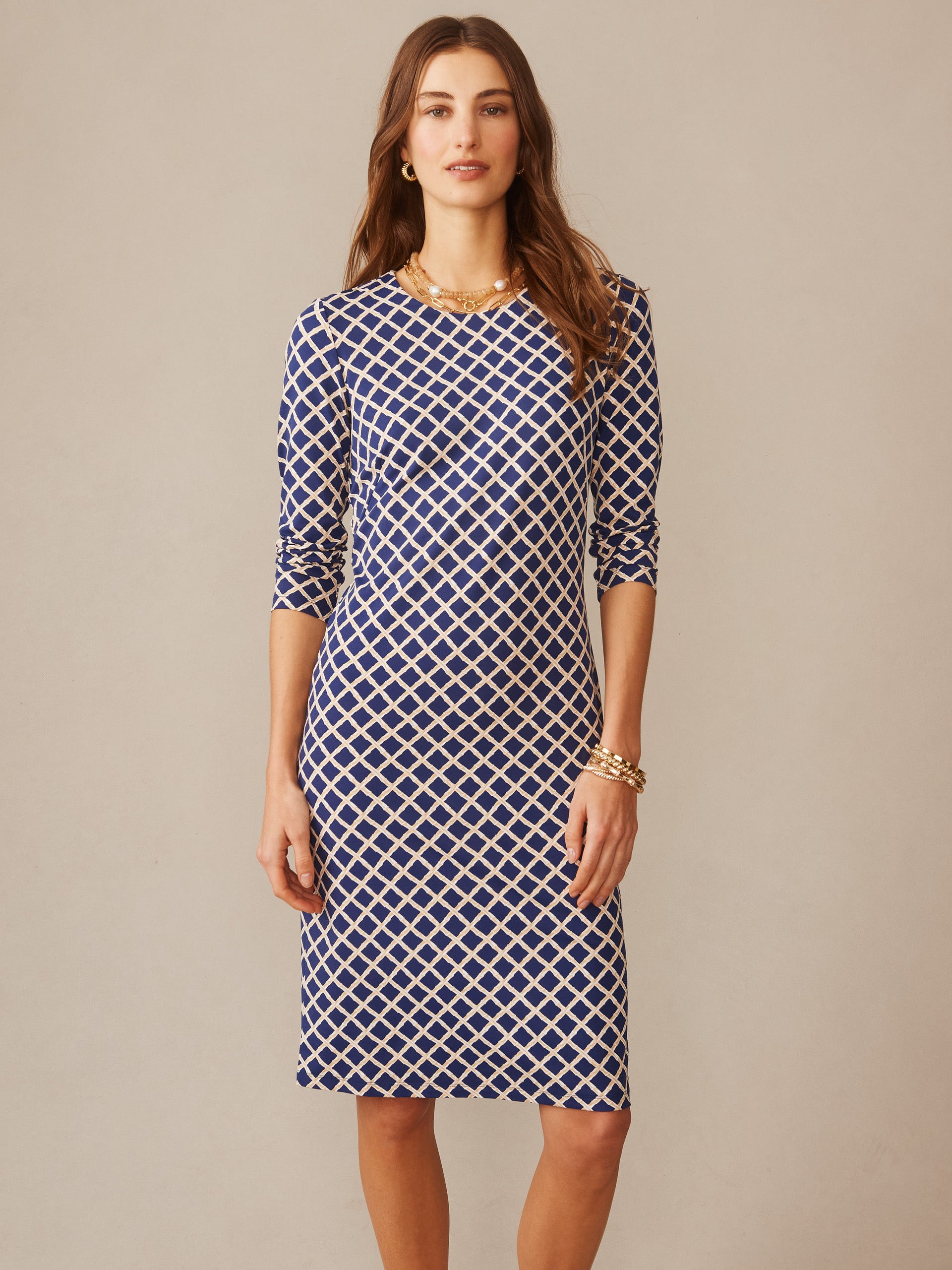 A model wears the Sophia Dress in Micro Bamboo by J.McLaughlin, featuring a navy and sand geometric pattern, showcasing effortlessly stylish, enduring designs with innovative fabrics from a destination for defining style. Life, Well-Lived.