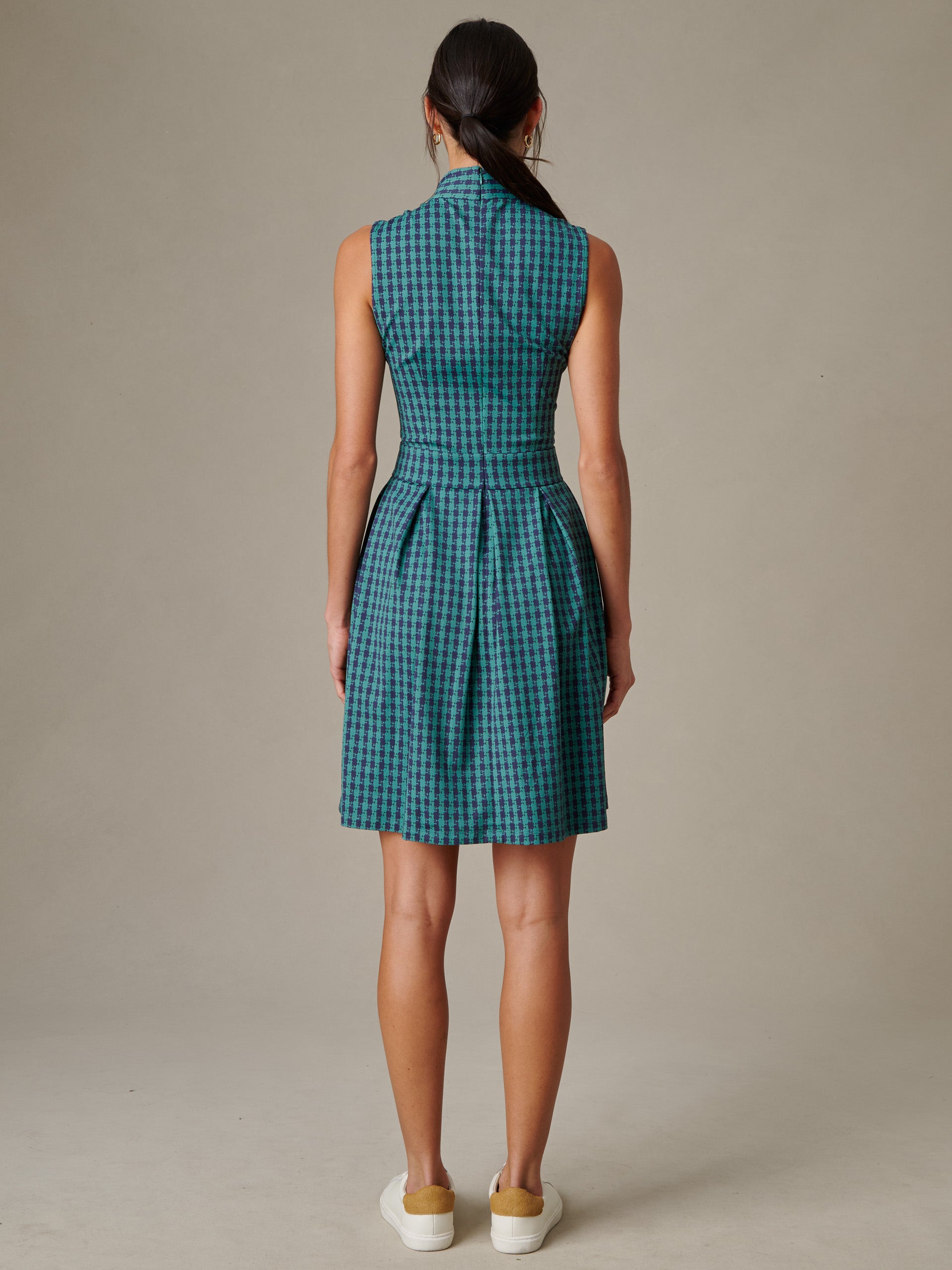 Woman seen from the back wearing the Steffi Dress in Algiers Check by J.McLaughlin, a sleeveless, tailored dress featuring a blue and green check pattern, styled with casual white sneakers.