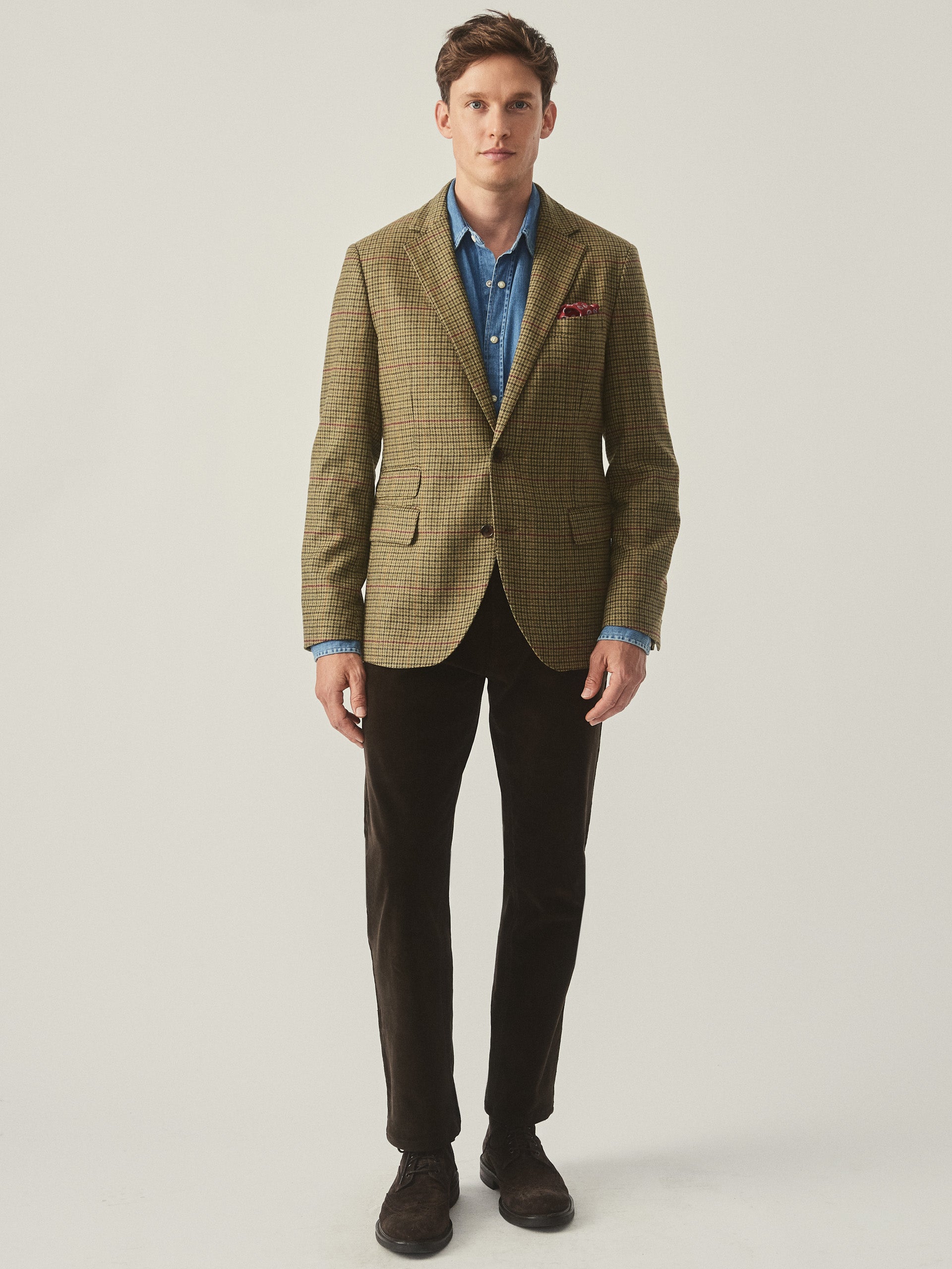 Model wearing J.McLaughlin Suffolk blazer in brown/green/red/mustard made with wool.