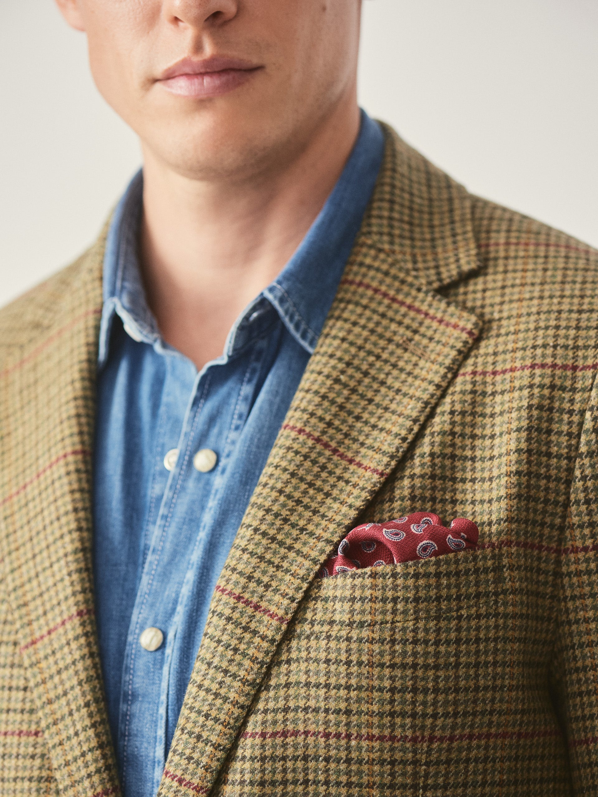 Model wearing J.McLaughlin Suffolk blazer in brown/green/red/mustard made with wool.
