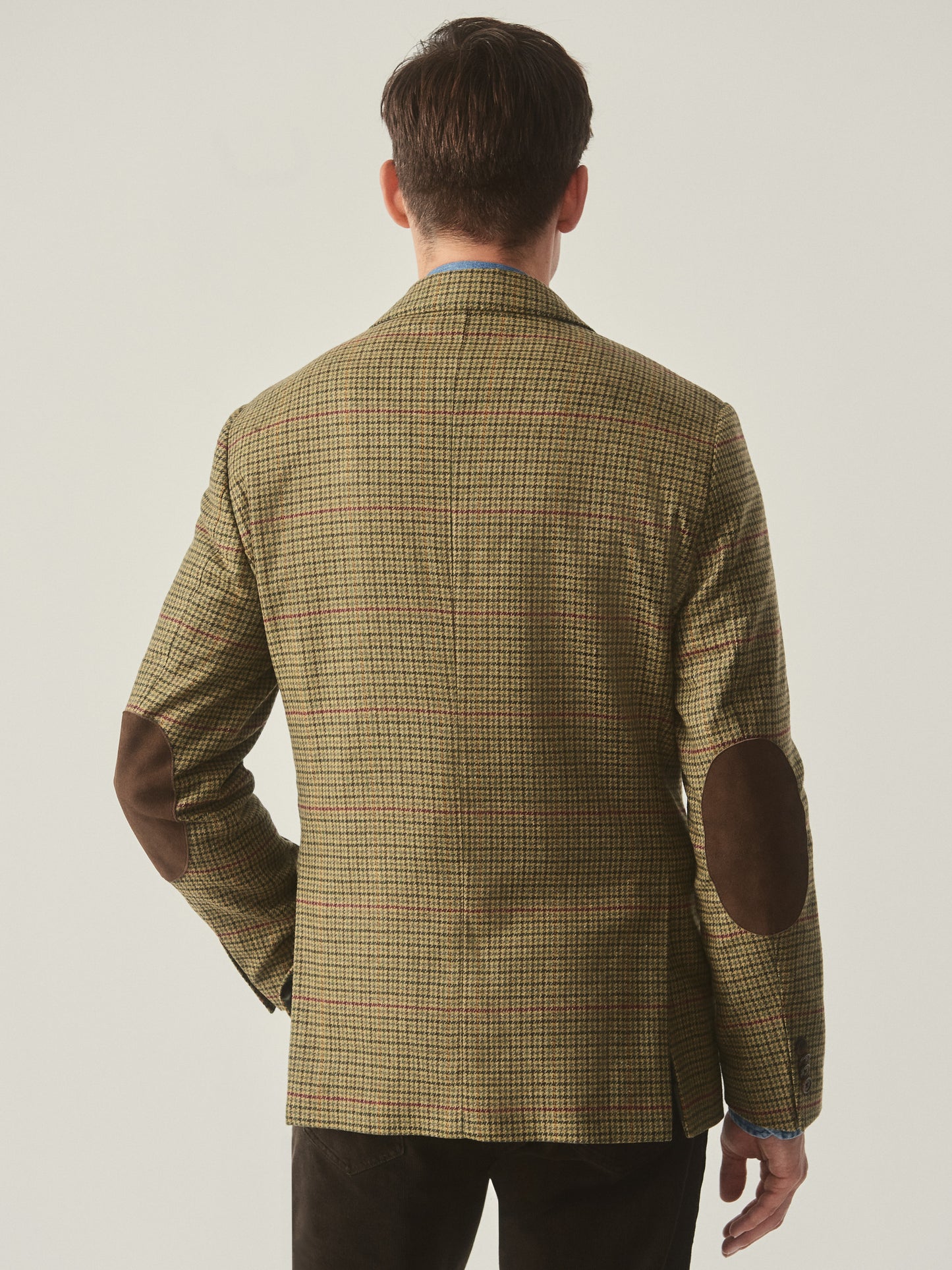Model wearing J.McLaughlin Suffolk blazer in brown/green/red/mustard made with wool.