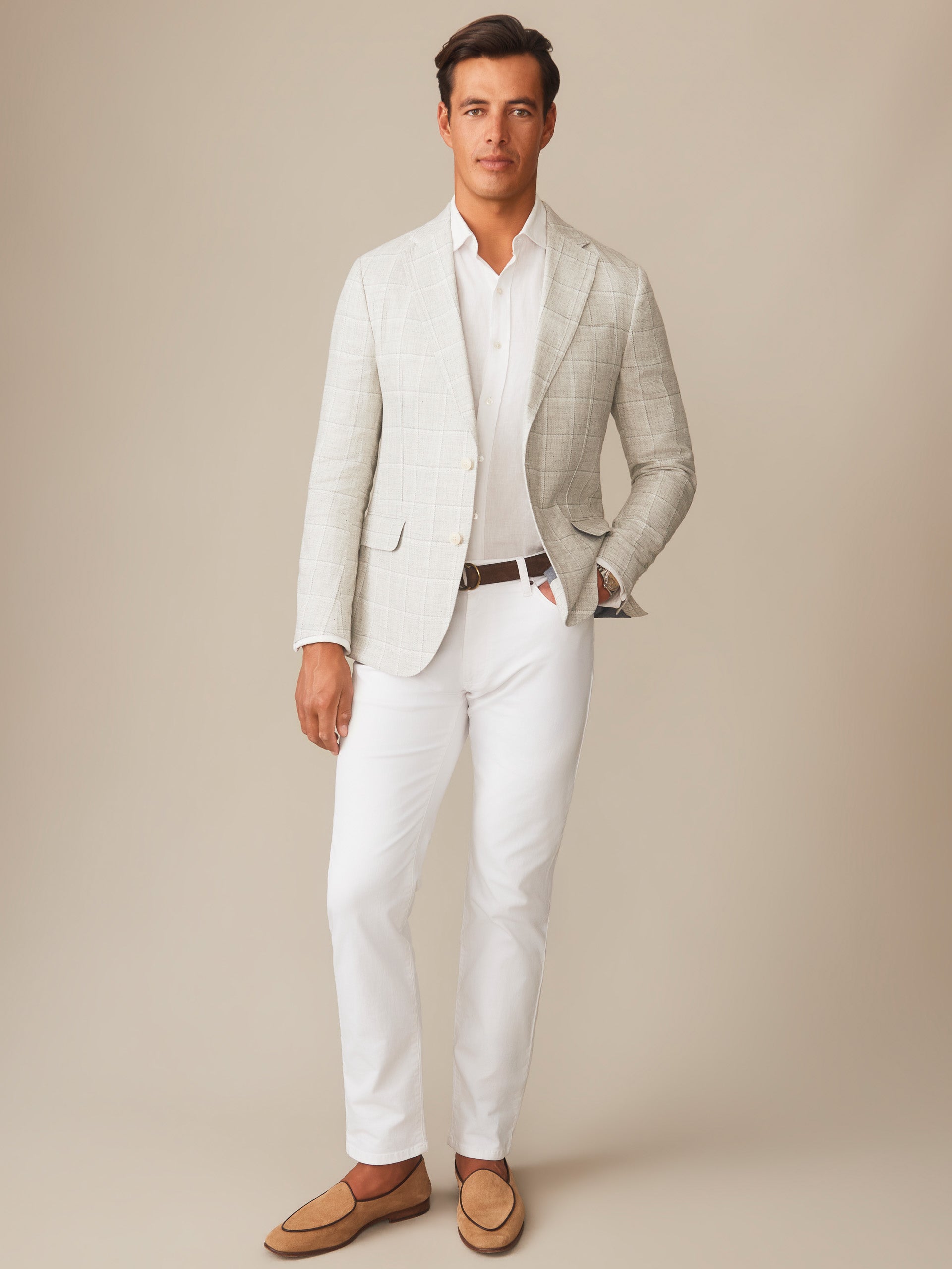 A man wears a Suffolk Linen Sport Coat in Window Pane by J.McLaughlin over a white shirt and pants with tan loafers, showcasing effortlessly stylish, enduring designs and innovative fabrics.