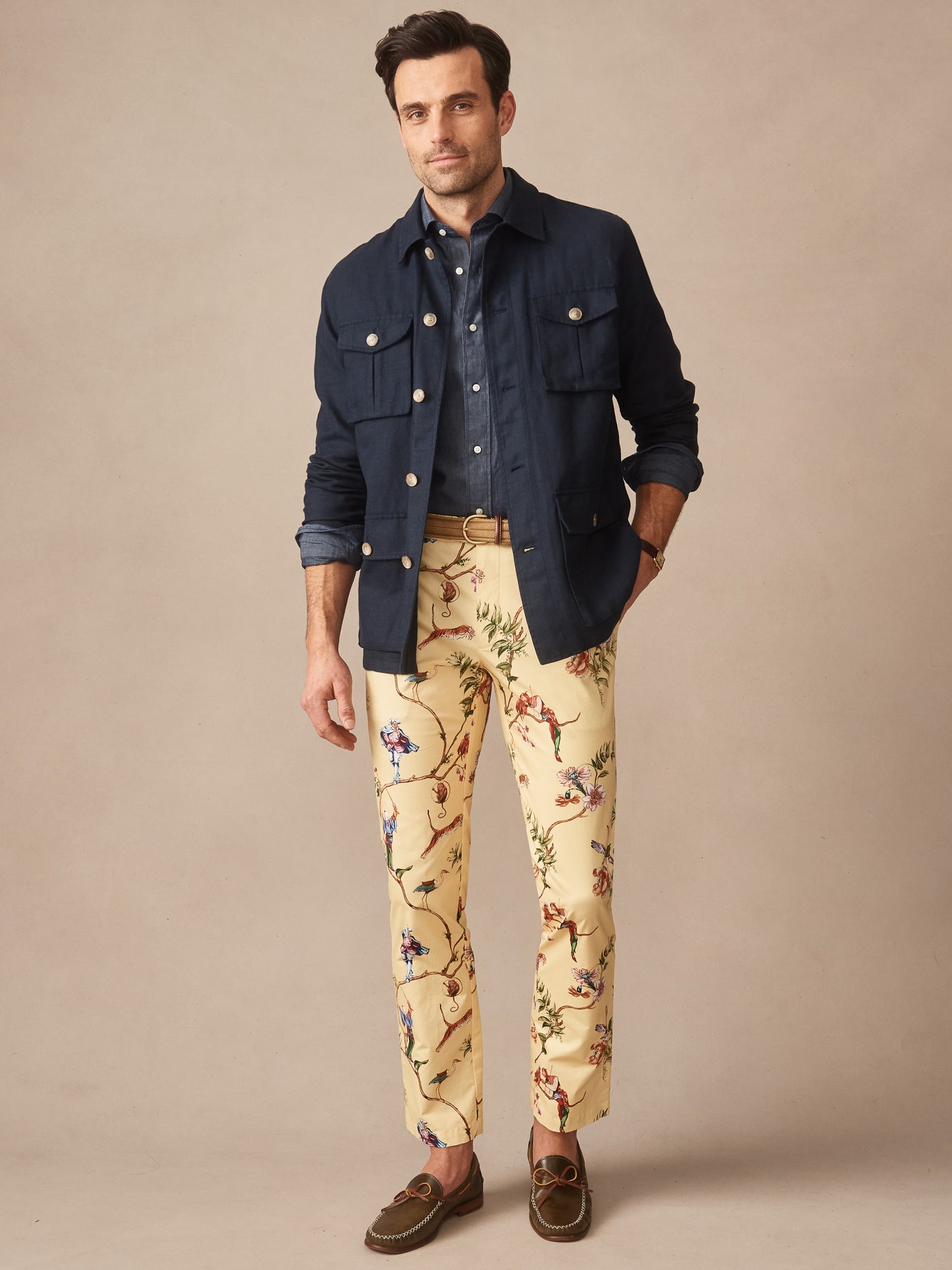 Male model wearing Madison Fancy Pants in Garden Spectacle by J.McLaughlin, paired with a navy jacket and shirt, showcasing effortlessly stylish, enduring designs with innovative fabrics. A destination for defining style. Life, Well-Lived.