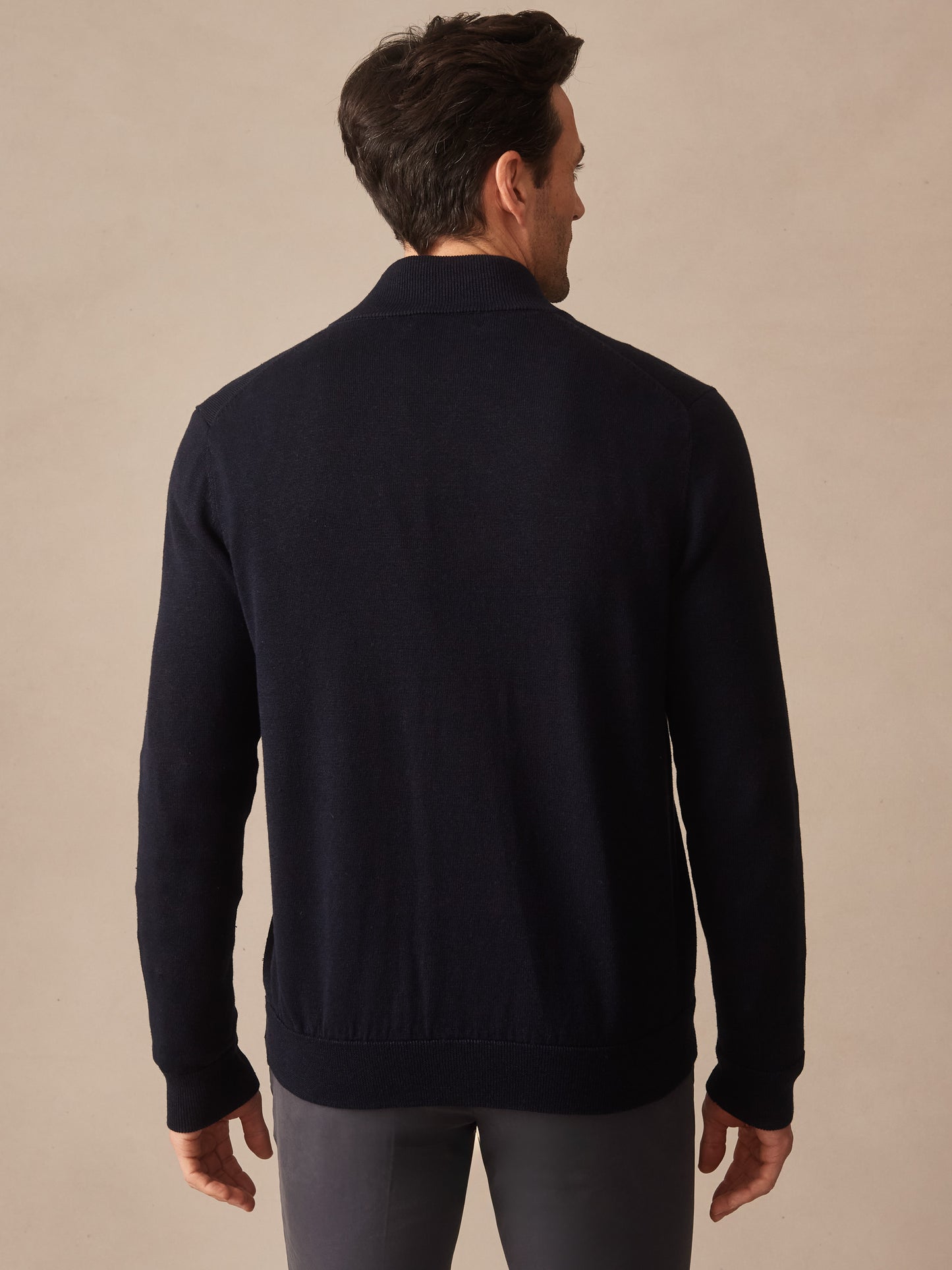 Man wearing a dark navy Orwell Sweater by J.McLaughlin, showcasing effortlessly stylish, enduring designs with innovative fabrics for a legacy of timeless fashion.