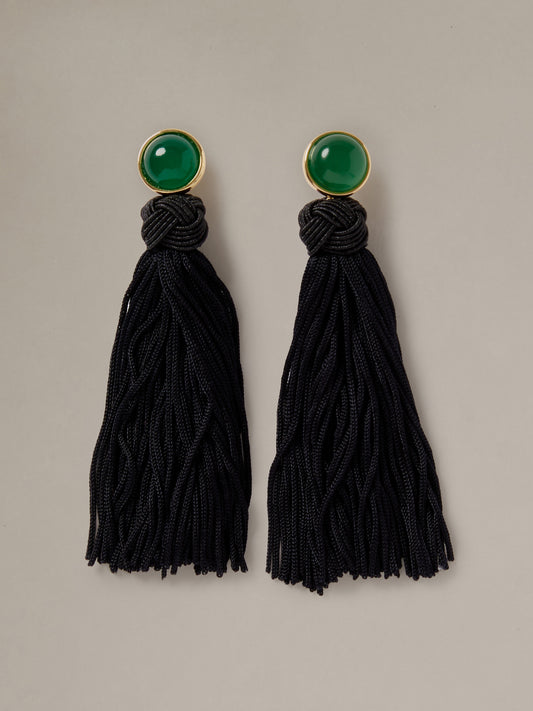 J.McLaughlin Tassel Earrings with round green semi precious stones and long black knotted tassels on a neutral background