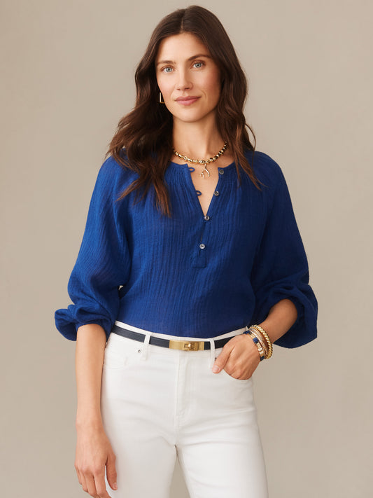 Woman wearing a nautical navy Tatiana Linen Blouse by J.McLaughlin styled with white pants and gold accessories, showcasing effortlessly stylish and enduring designs in innovative fabrics. A destination for defining style. Life, Well-Lived.