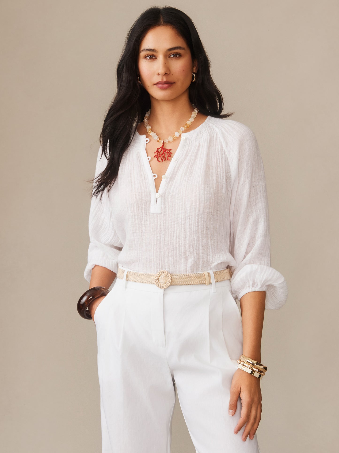 Woman wearing a white Tatiana Linen Blouse by J.McLaughlin paired with white pants and accessories, showcasing effortlessly stylish, enduring designs with a legacy of timeless fashion.