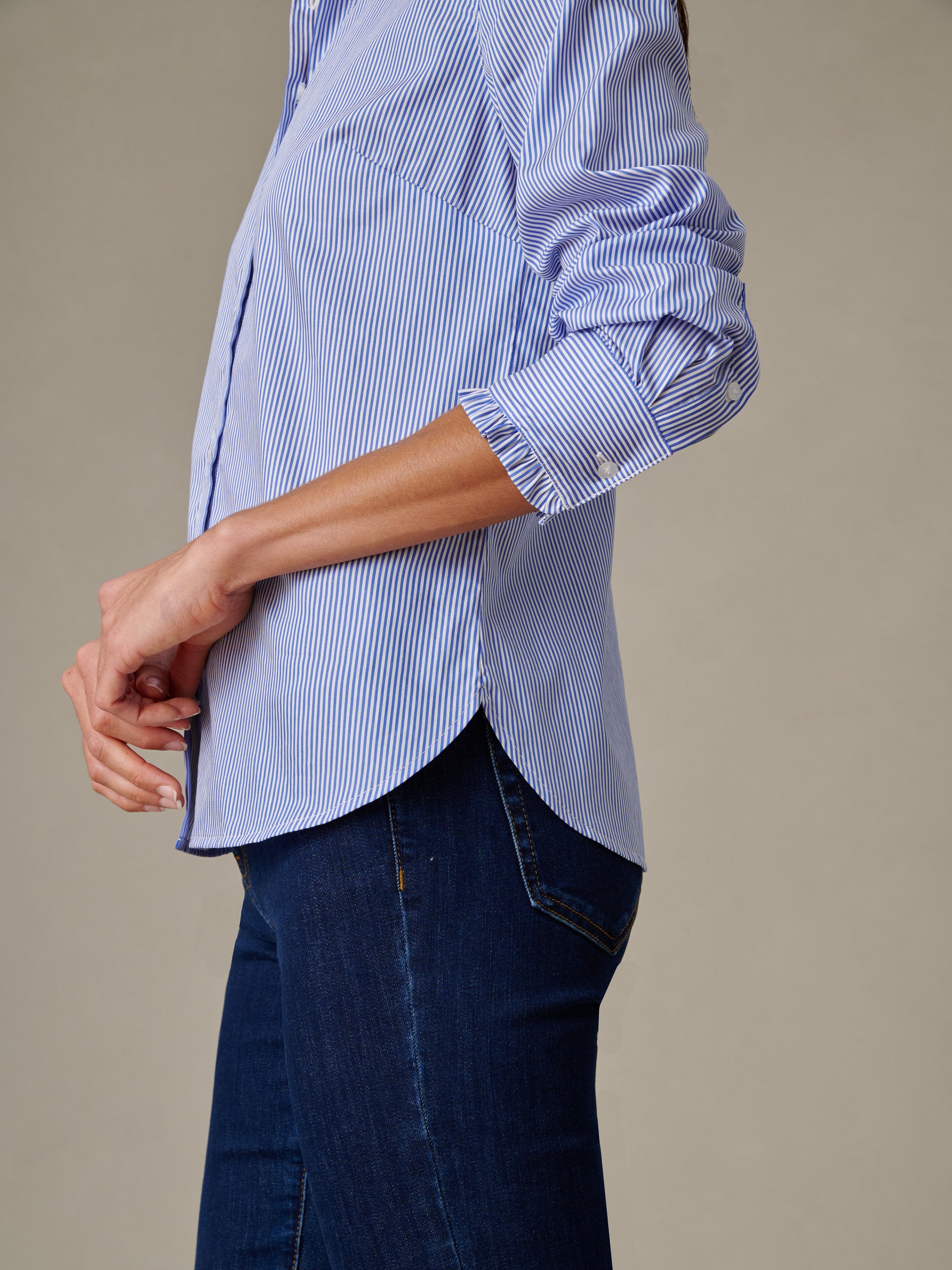 Side view of a person wearing the Tess Ruffle Collar Shirt in Stripe by J.McLaughlin, showcasing classic blue and white stripes and refined craftsmanship for a timeless, effortlessly stylish look.