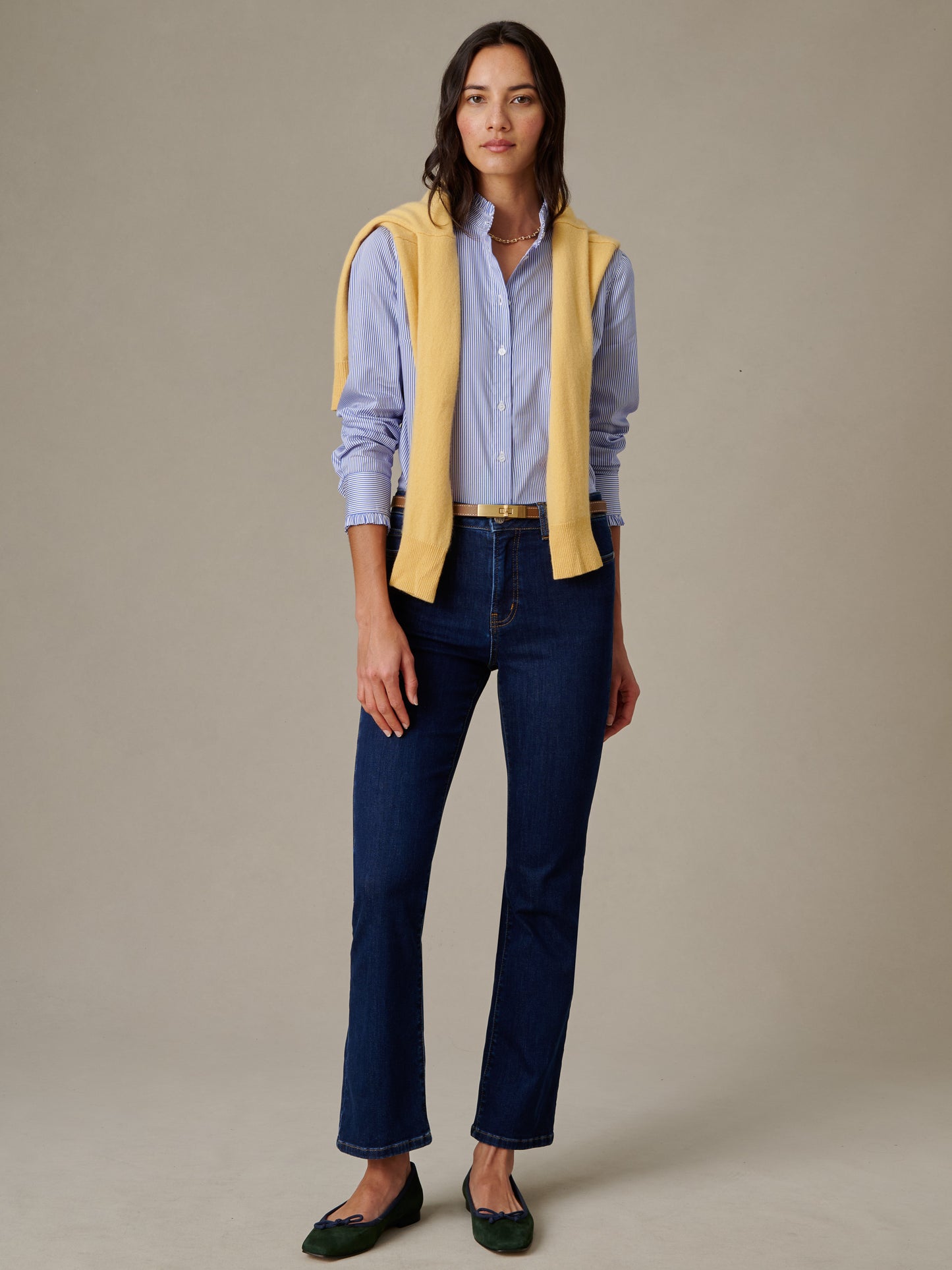Woman wearing Tess Ruffle Collar Shirt in Stripe by J.McLaughlin paired with dark jeans and a yellow sweater draped over shoulders, embodying effortless style and timeless fashion.
