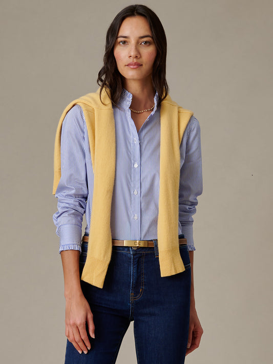 Woman wearing Tess Ruffle Collar Shirt in Stripe by J.McLaughlin paired with dark jeans and a yellow sweater draped over shoulders, embodying effortless style and timeless fashion.
