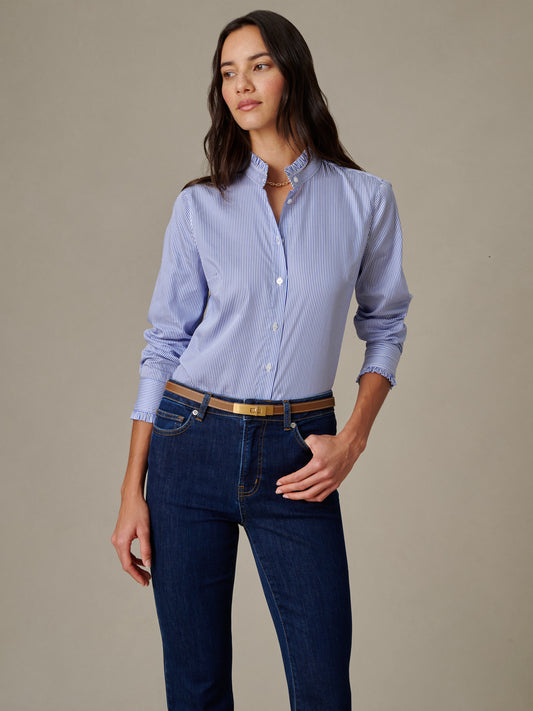 Woman wearing a striped Tess Ruffle Collar Shirt in Stripe by J.McLaughlin paired with dark jeans and a belt, showcasing effortlessly stylish, enduring design.