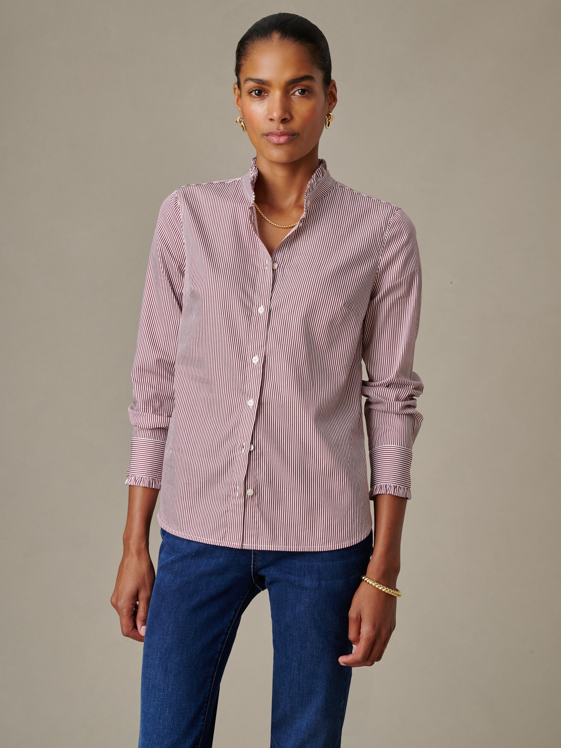 Woman wearing a striped Tess Ruffle Collar Shirt in Stripe by J.McLaughlin paired with blue jeans, showcasing an effortlessly stylish and timeless blouse design.