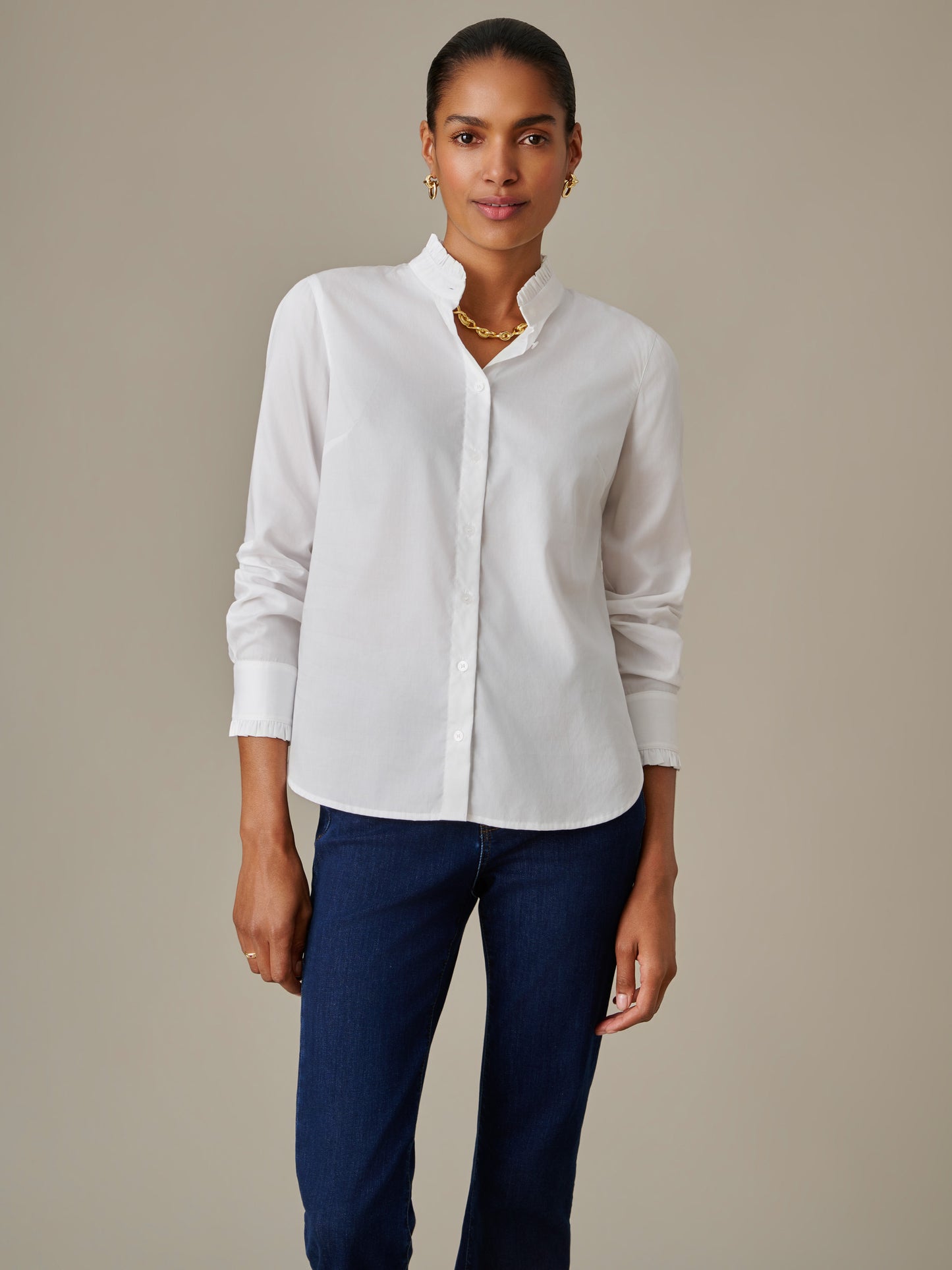 Woman wearing a white Tess Ruffle Collar Shirt by J.McLaughlin paired with dark blue jeans, showcasing a timeless and effortlessly stylish look with a ruffled collar detail.