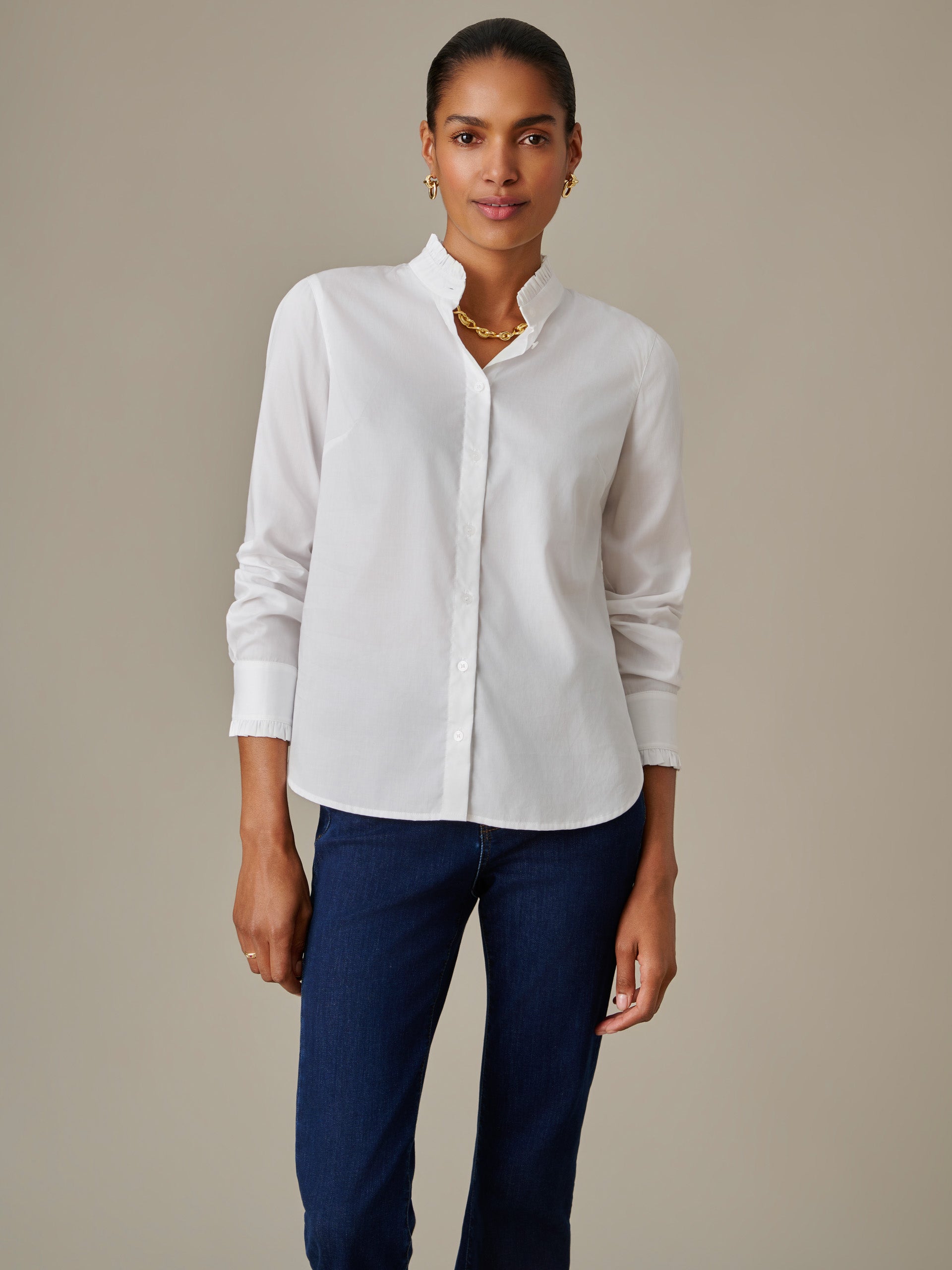 Woman wearing a white Tess Ruffle Collar Shirt by J.McLaughlin paired with dark blue jeans, showcasing a timeless and effortlessly stylish look with a ruffled collar detail.
