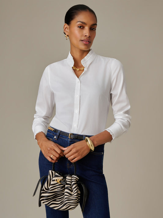 Woman wearing white Tess Ruffle Collar Shirt by J.McLaughlin styled with dark jeans, gold jewelry, and holding a zebra-print bag, showcasing timeless, classic fashion.